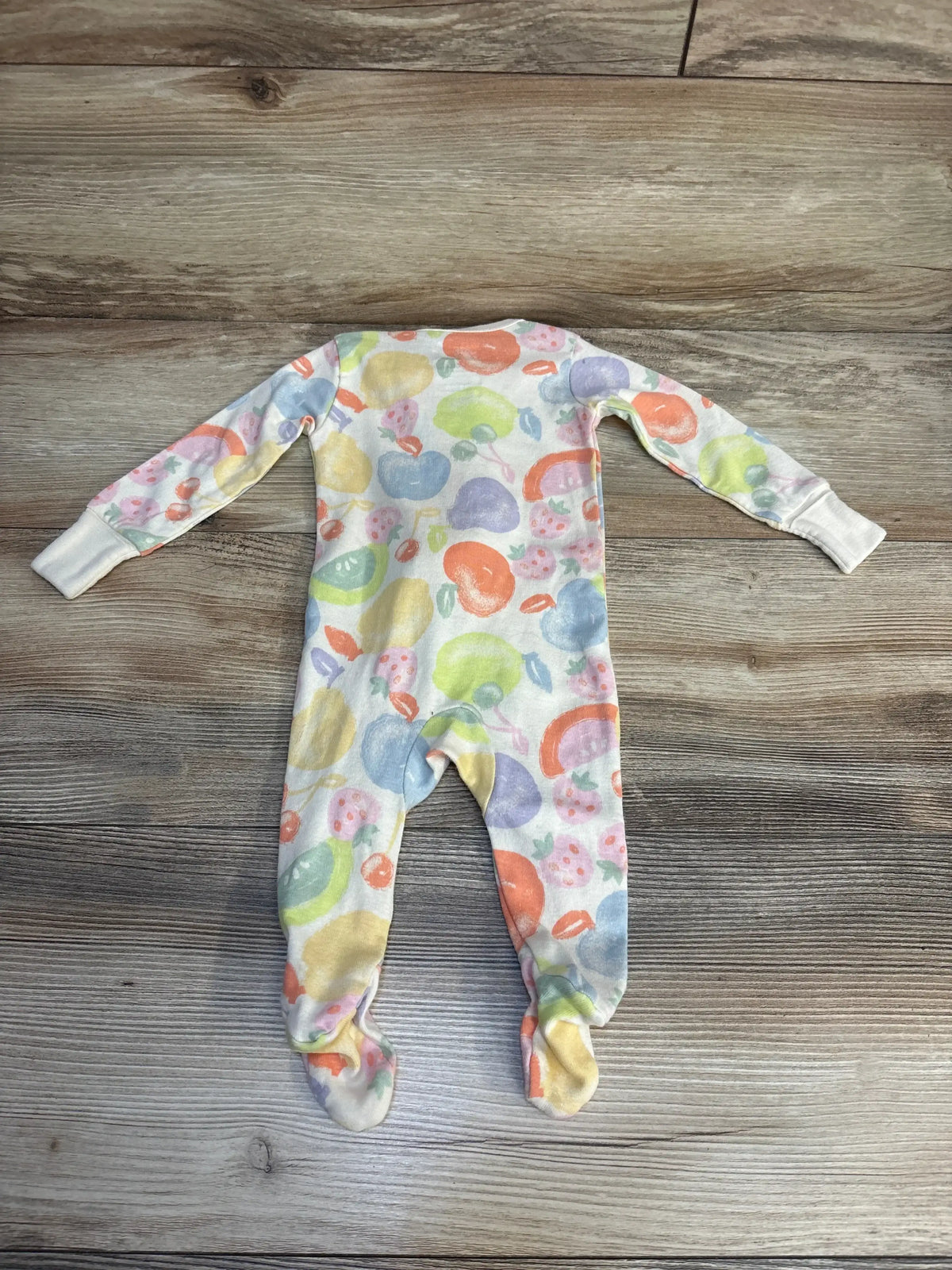 Colorful fruit print baby footed sleeper laid flat on wood floor
