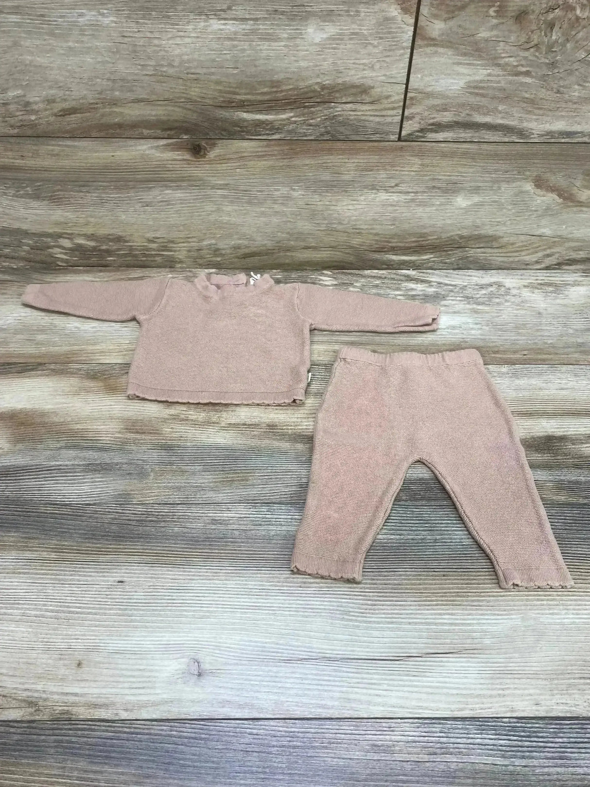 Flat lay of brown knit baby sweater and matching pants, 0-3 months, showing ruffled collar and scalloped cuffs on wood