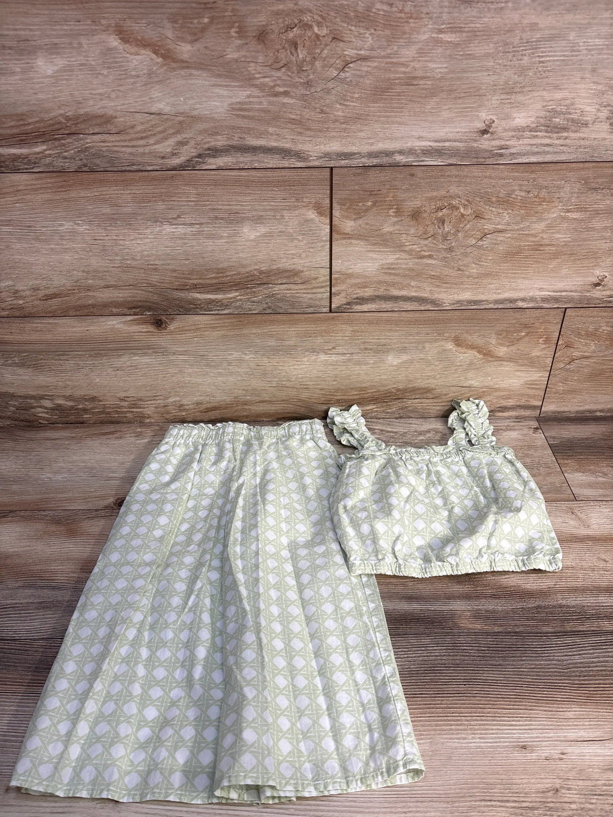 Flat lay of Janie & Jack green checked ruffle strap top and coordinating pants set on a wood floor