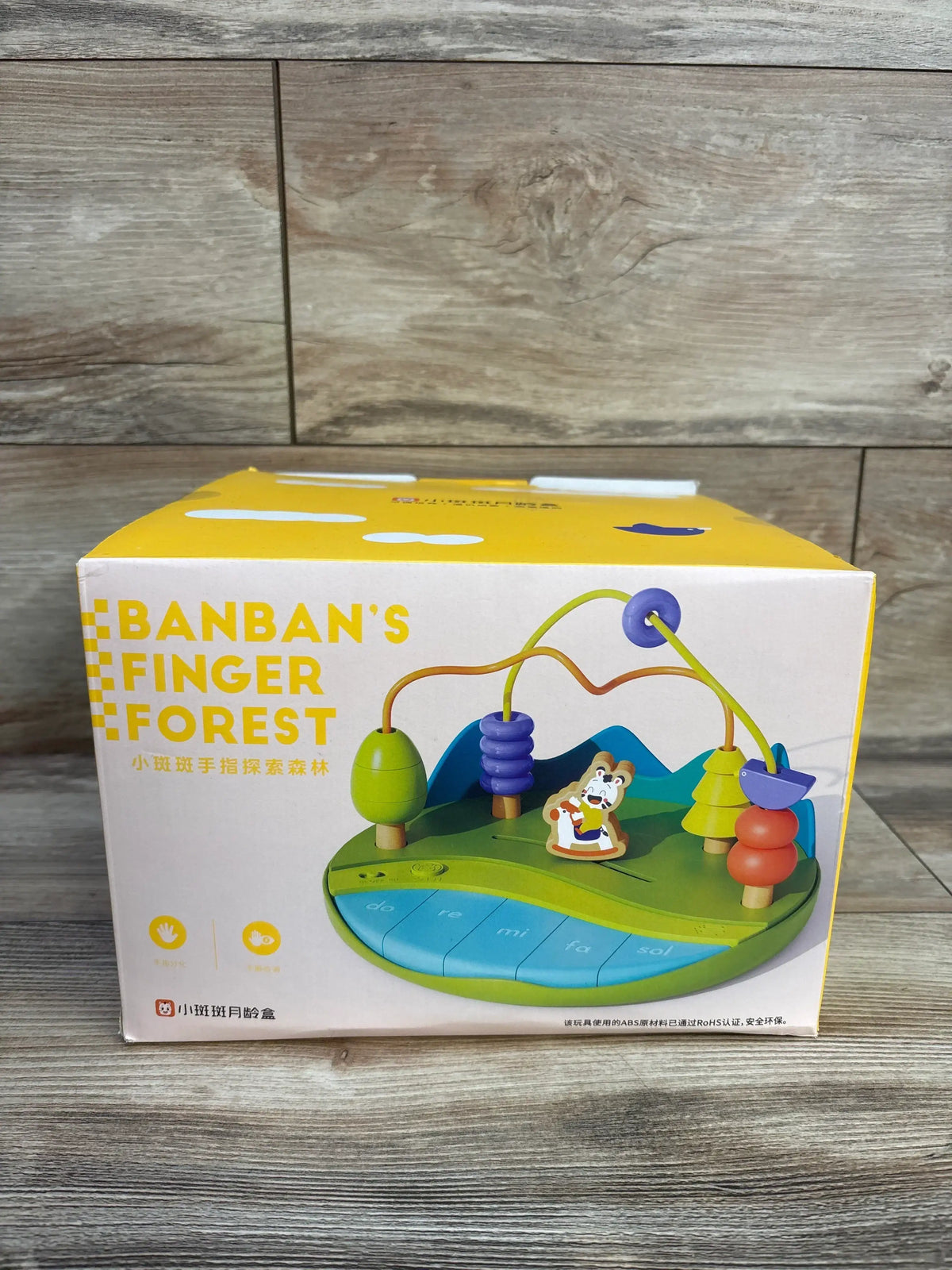Front of Banban’s Finger Forest toy box showcasing wooden bead maze and five-key xylophone with wood background