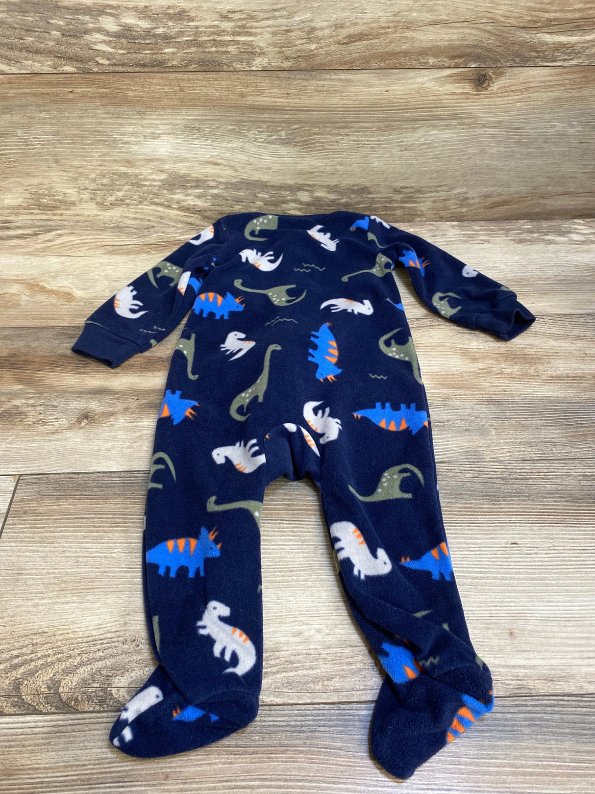Navy blue baby sleeper with colorful dinosaur print on wooden background