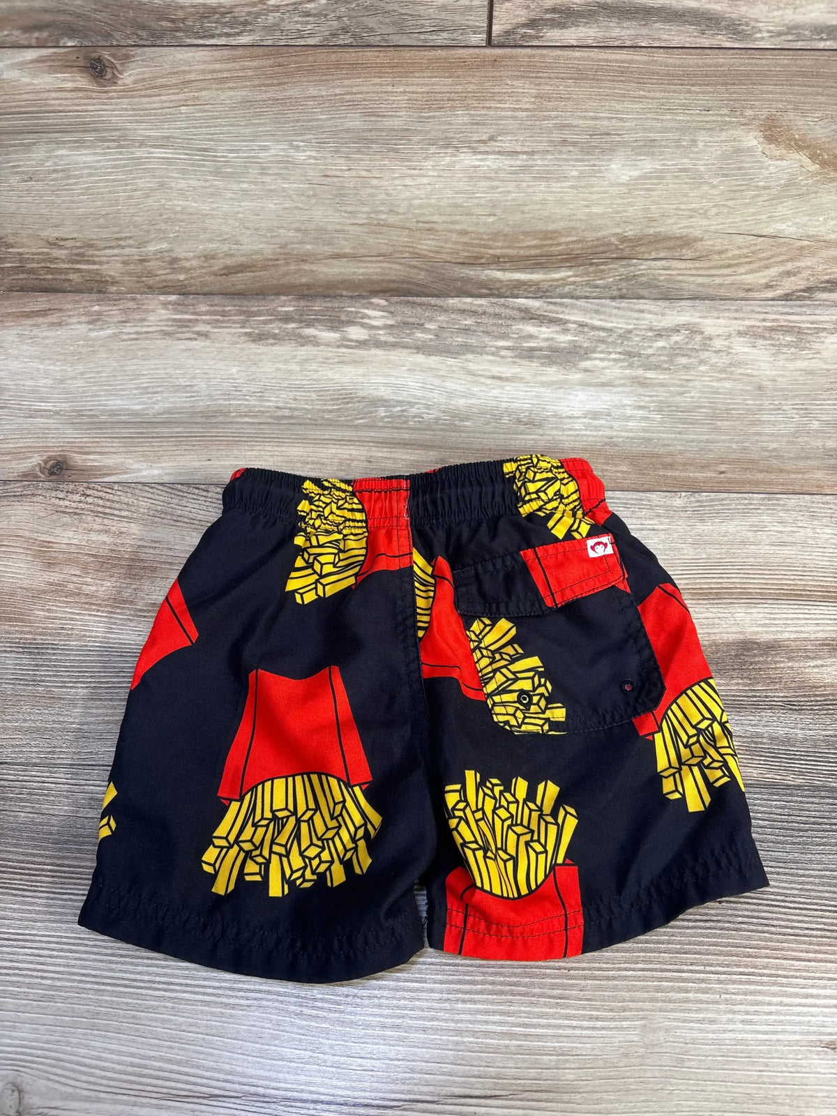 Front view of boys’ Appaman French Fry swim trunks in black showing elastic waistband and all-over french fry print on white background