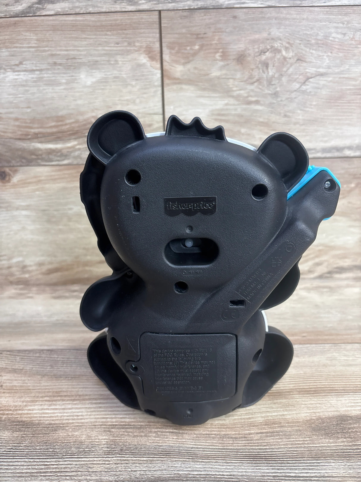 Back view of a black Fisher-Price plastic toy shaped like a lion, on a wooden surface