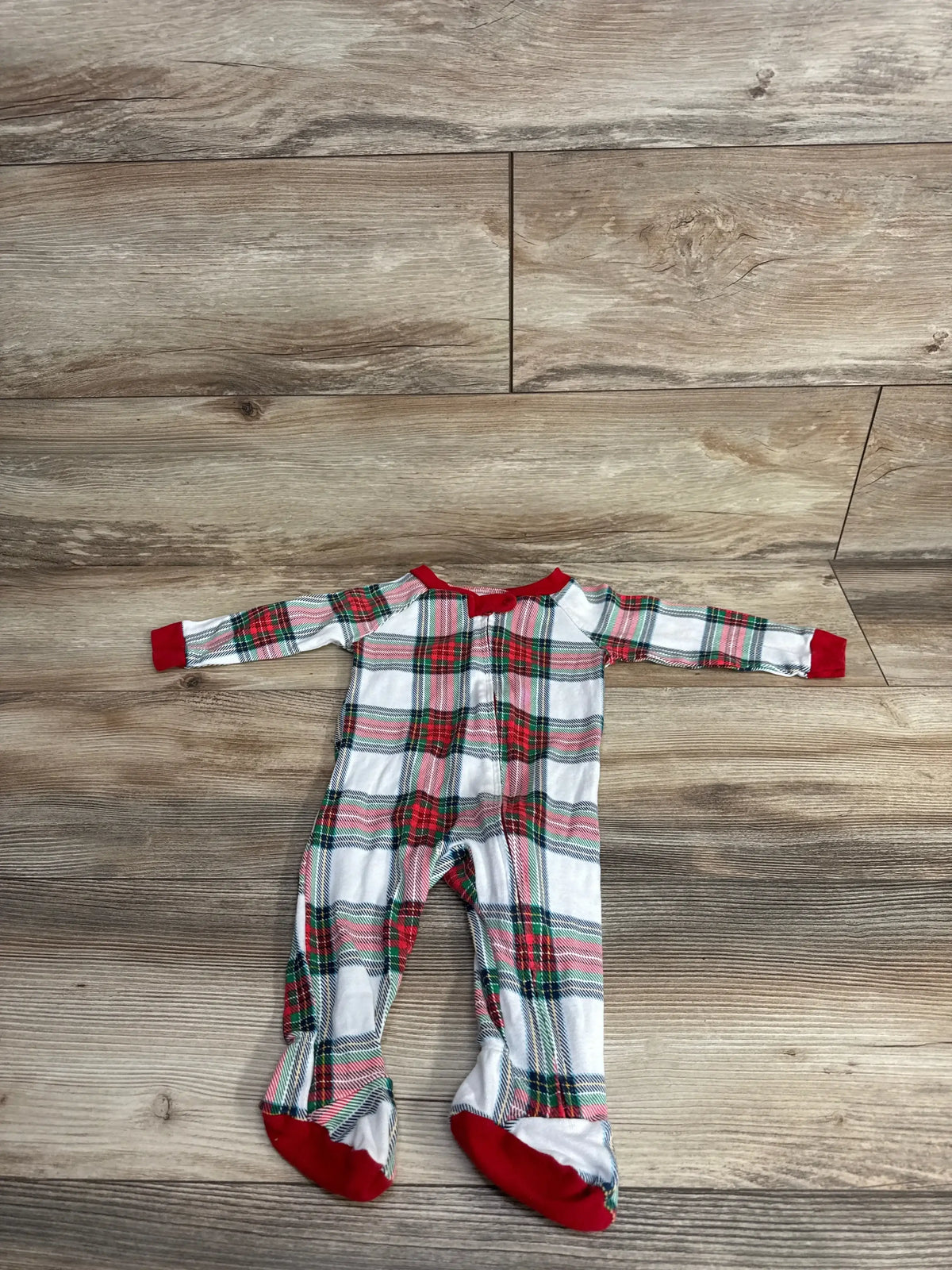 Red green plaid baby footed pajamas on wood floor, holiday kids sleepwear