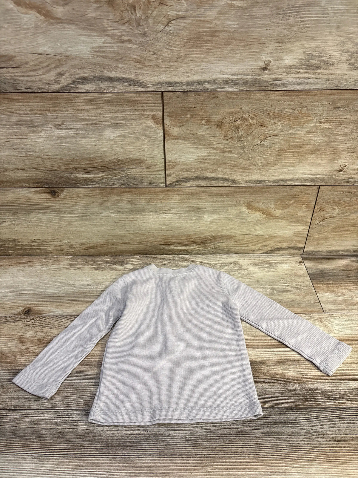 Back view of Jumping Beans grey waffle knit Henley shirt showcasing long sleeves and textured fabric on a wood floor
