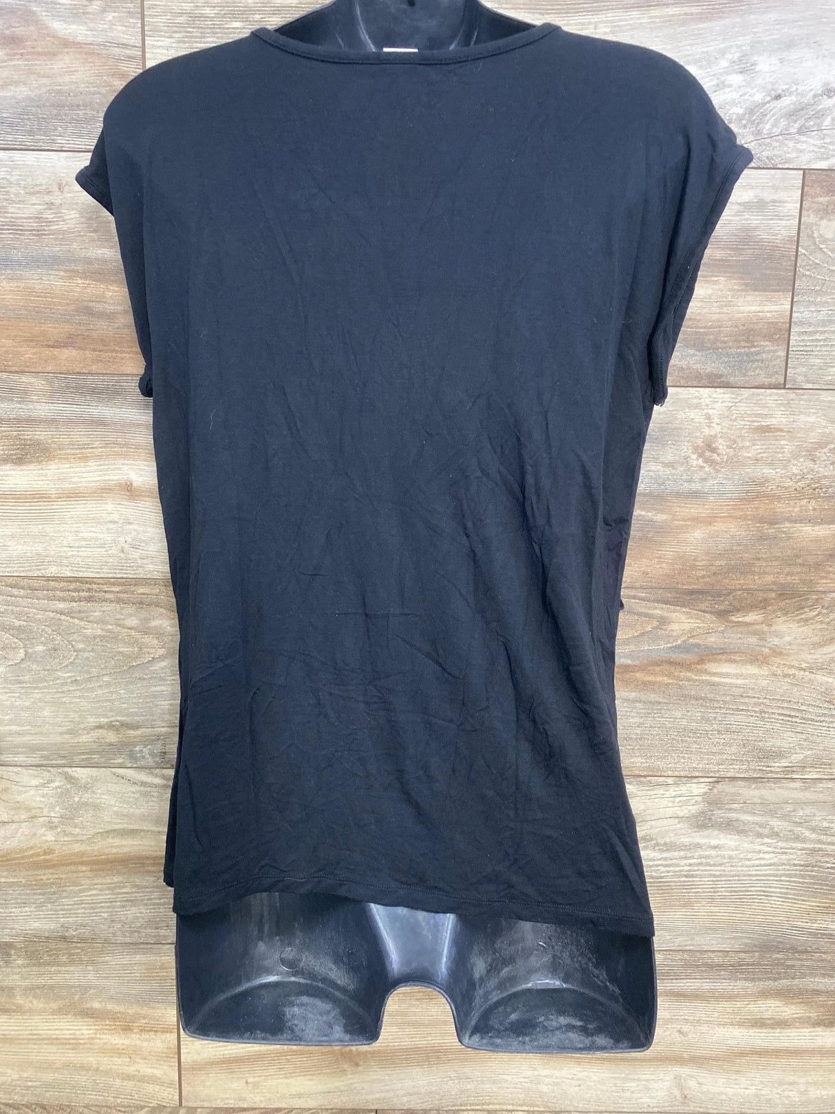 Front view of black maternity nursing shirt on mannequin showing cap sleeves and straight hem on wood background