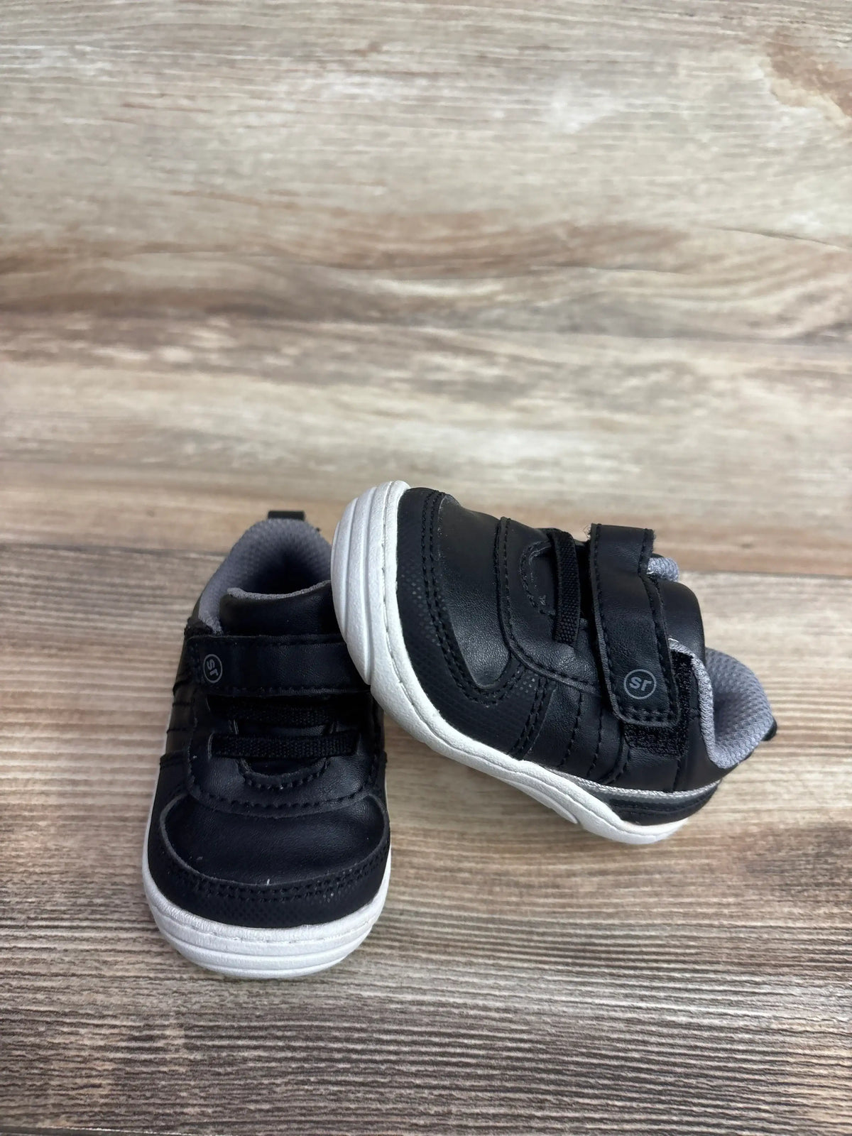 Front and side view of Stride Rite Killian black toddler sneakers size 3C with Velcro strap and white soles on wood floor