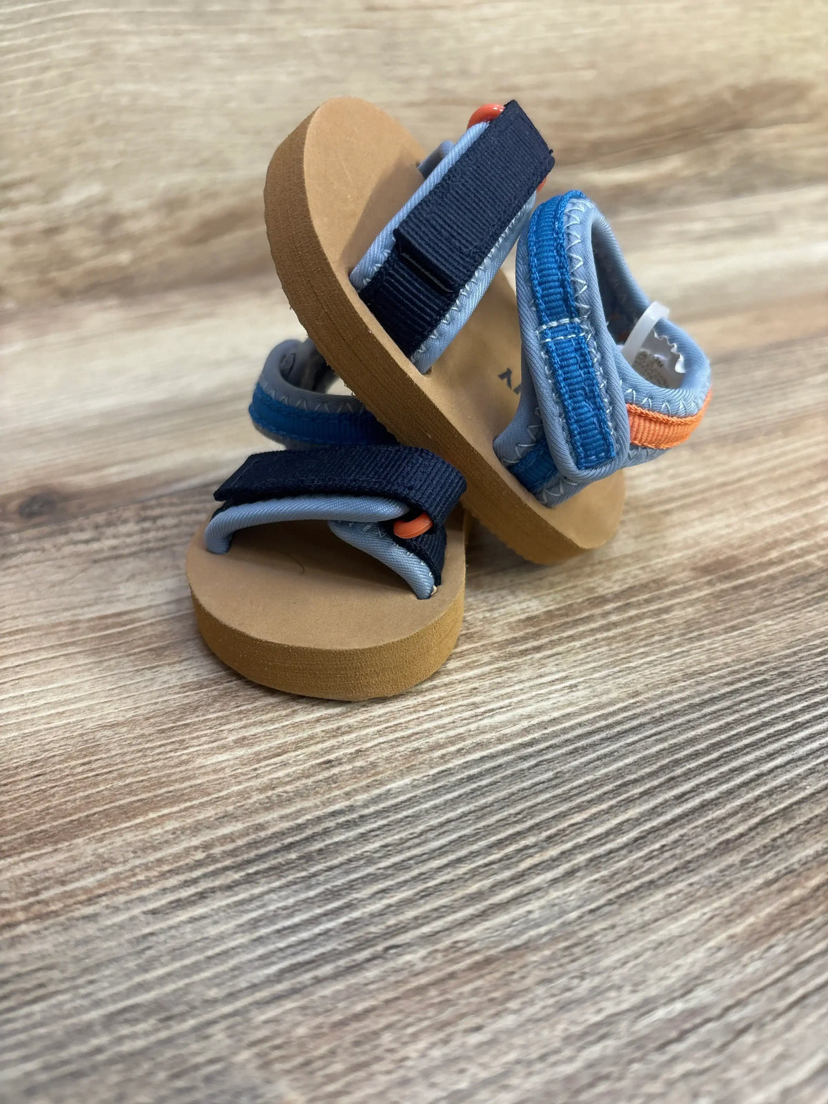 Angled view of Wonder Nation Sports Slides showcasing open toes and textured footbeds with a wood-grain background