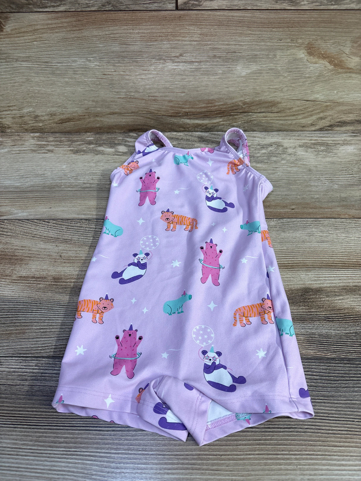 Front view of pink toddler leotard size 2T showcasing multicolored animal print, thin shoulder straps, and attached shorts on wooden background