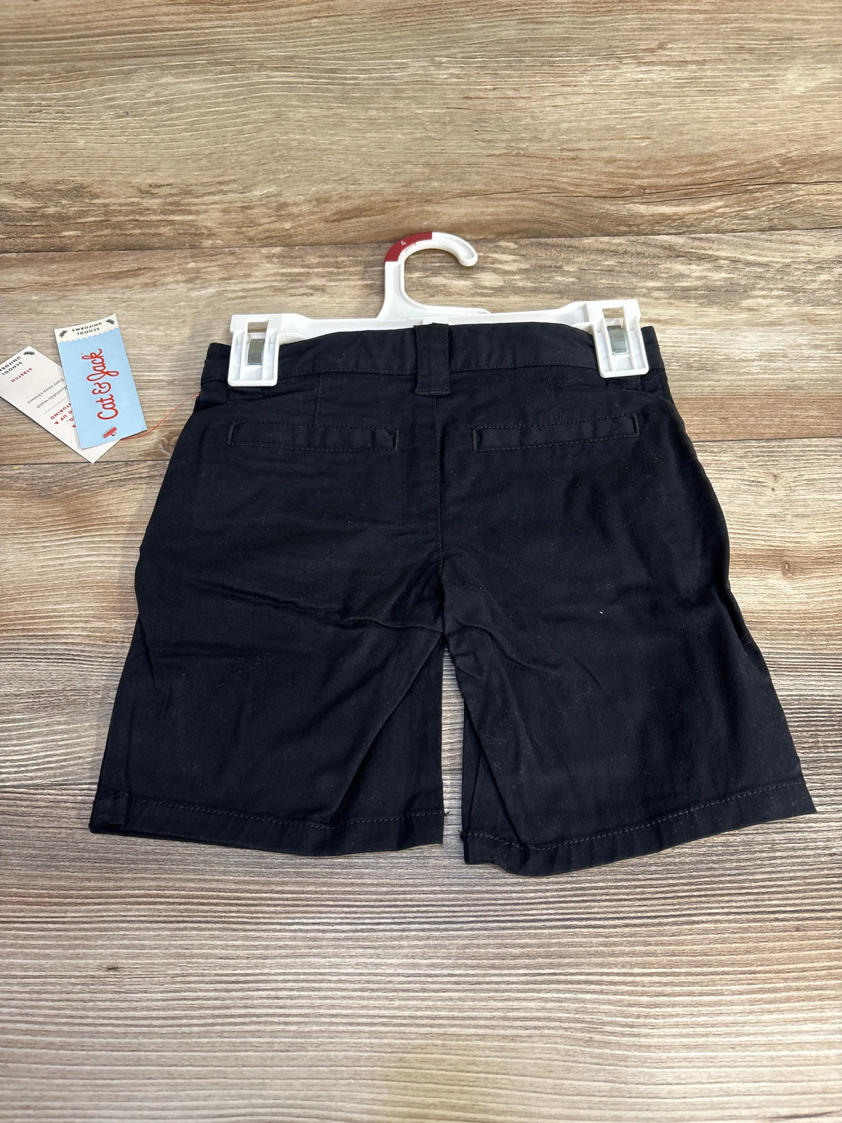 Rear view of Cat & Jack black school uniform shorts size 4T showing back welt pockets and belt loops on wood background