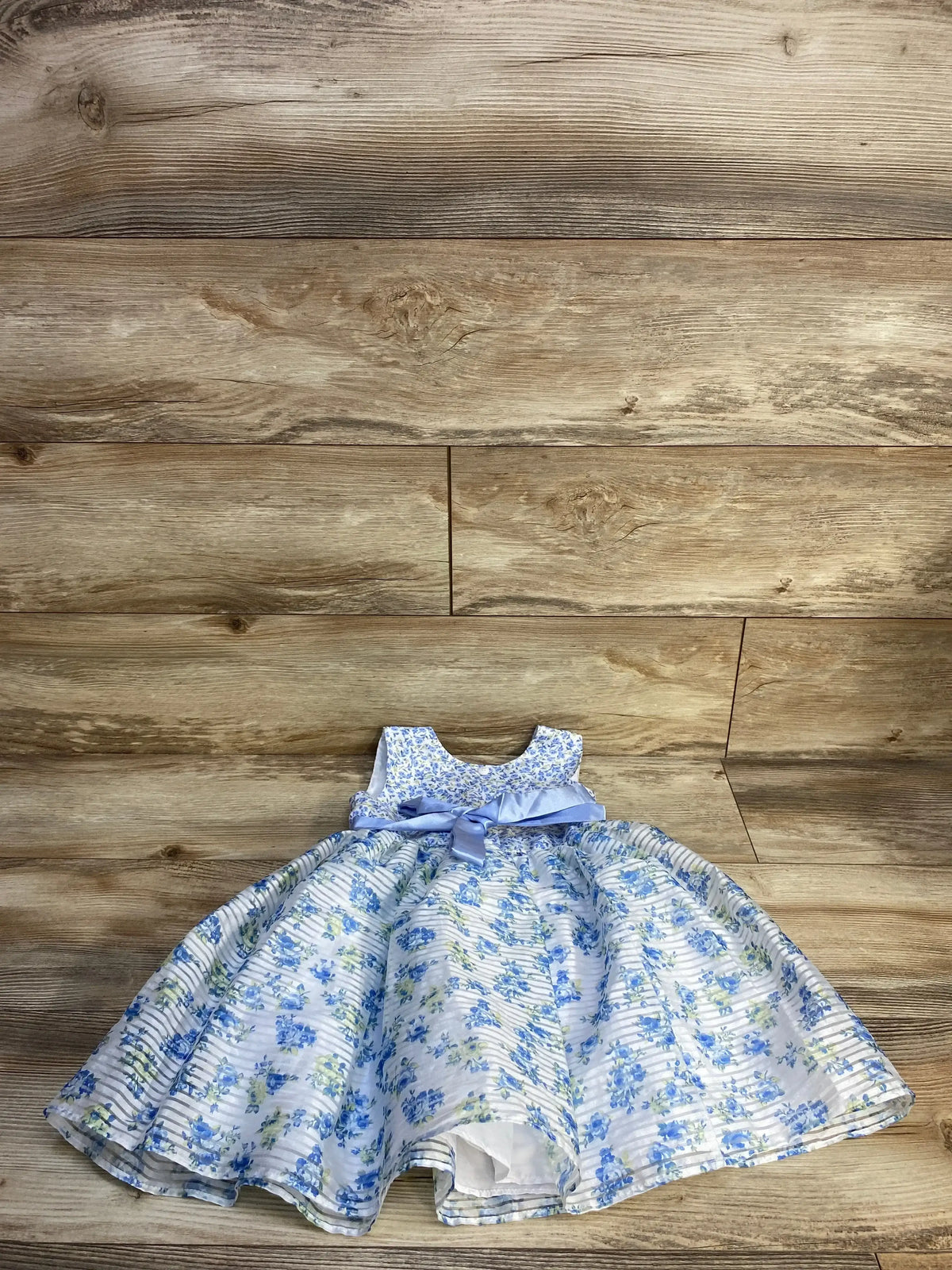 Flat lay of Jona Michelle blue sleeveless floral toddler dress size 3T showing bow sash and full skirt on wood background