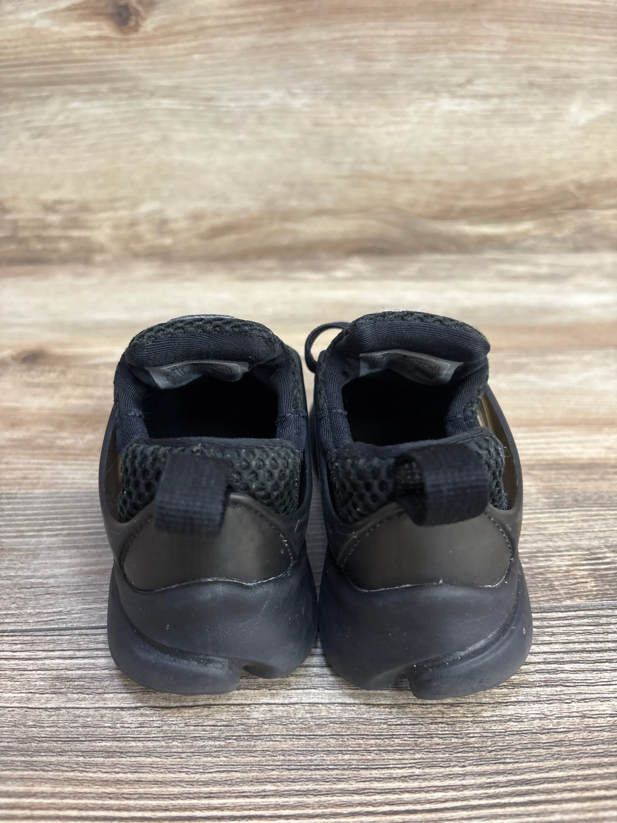 Rear view of Nike Little Presto TD toddler black sneakers size 8C showing mesh heel and pull tab on wood floor