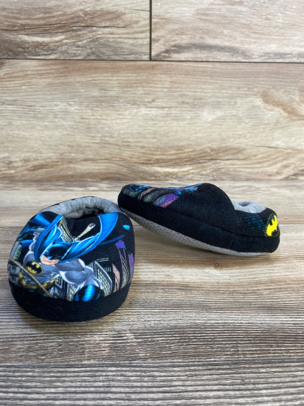 Kids Batman soft slipper shoes with superhero graphic on a wood floor