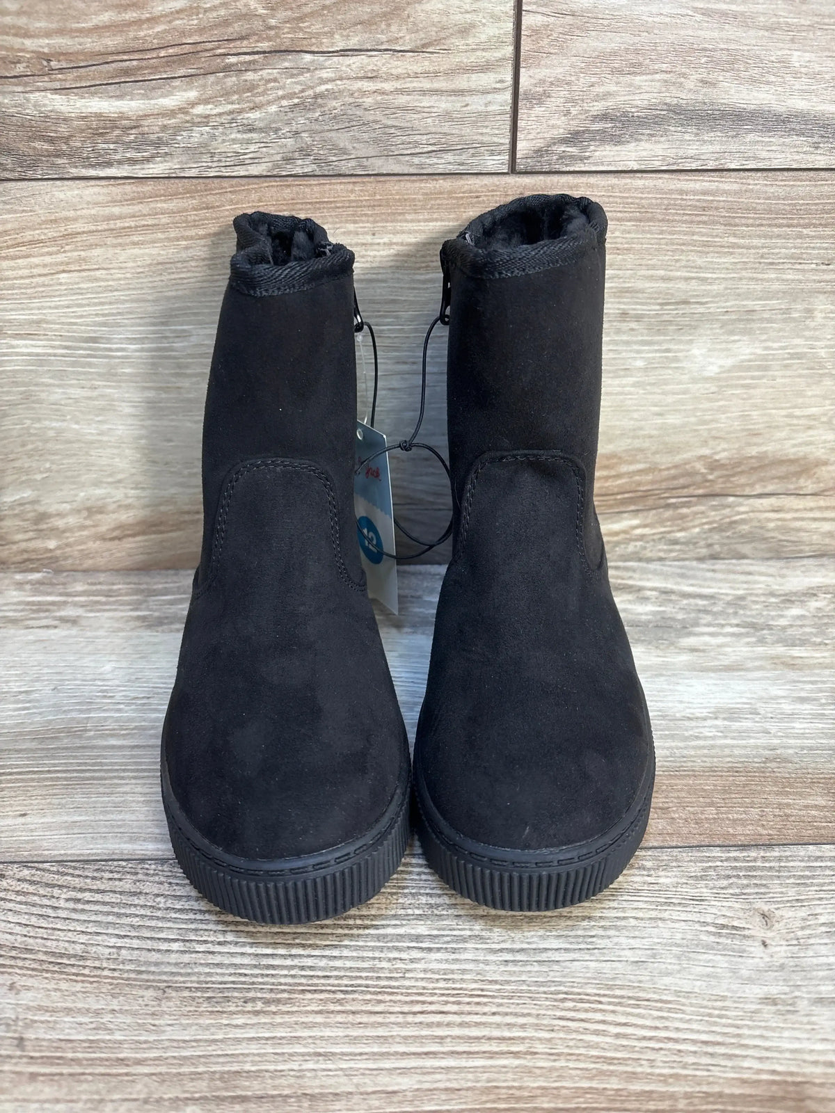 Pair of black kids suede ankle boots with rubber soles on wooden floor