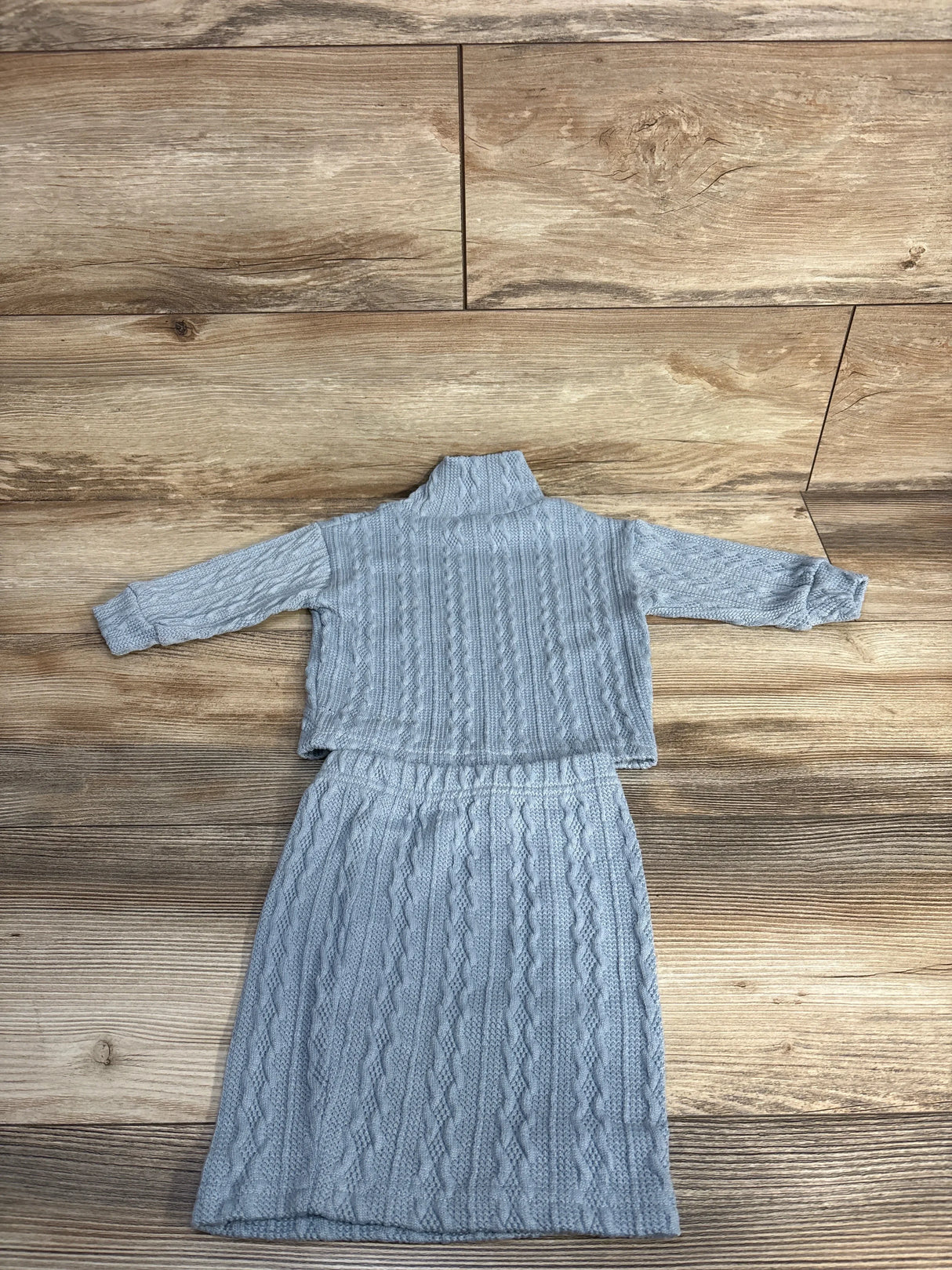 Gray cable knit sweater and skirt set on wood background