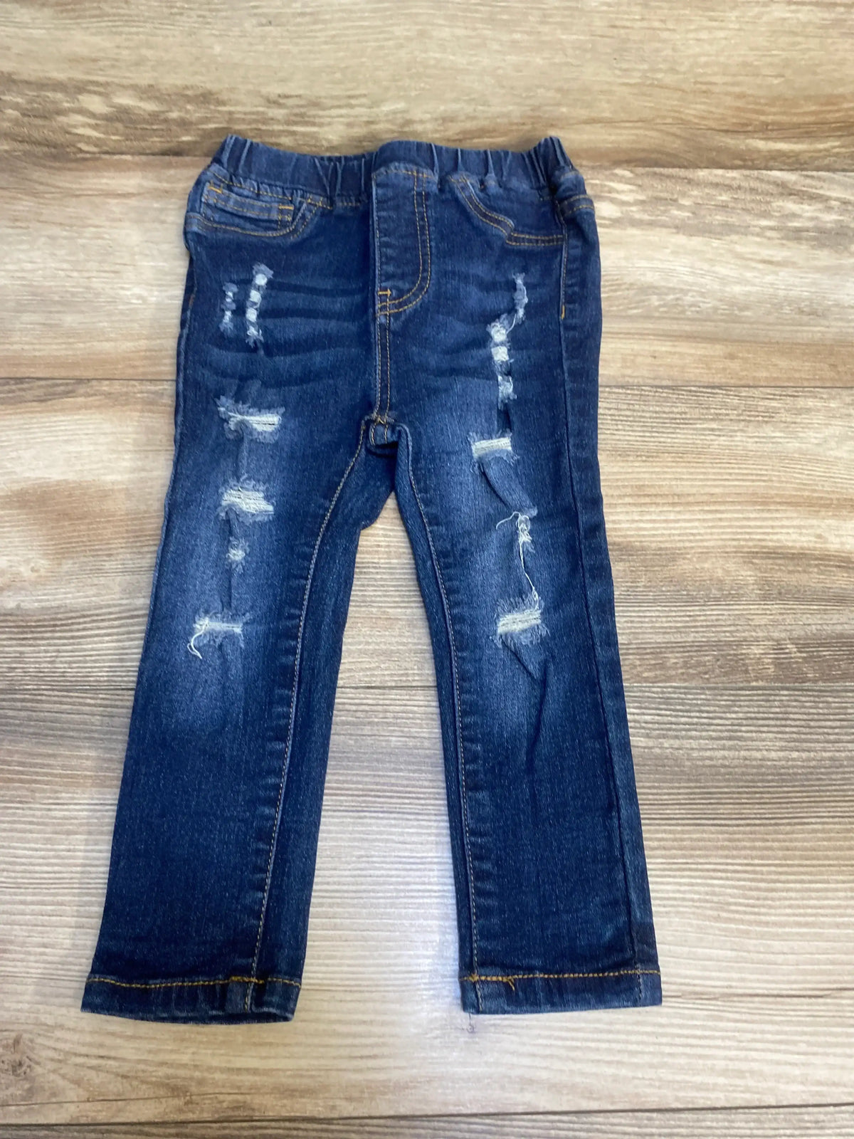 Dark wash distressed kids jeans with elastic waistband on wooden background