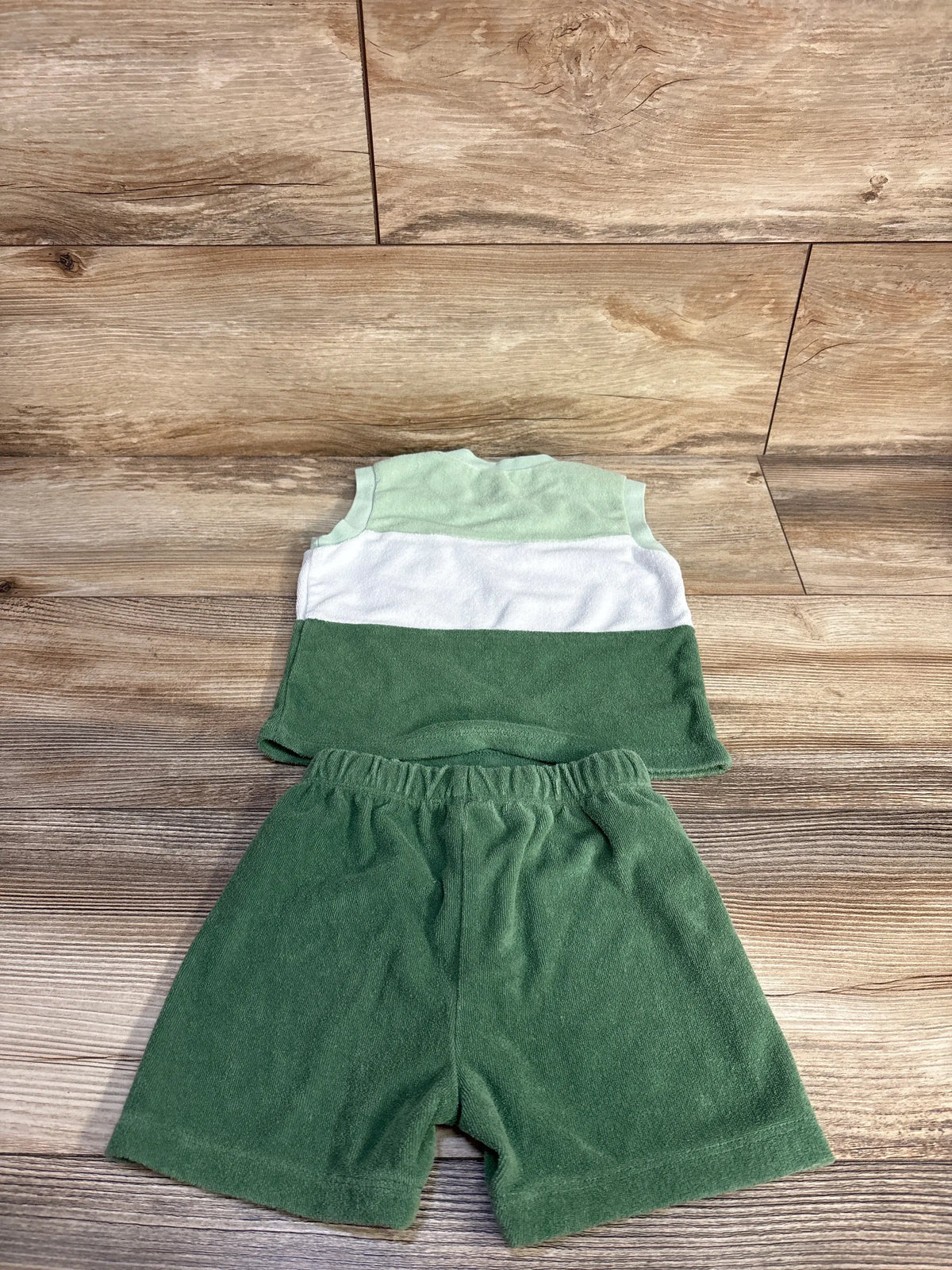 Top view of PL Baby two piece terry tank top and shorts set showcasing green color blocking with wood floor background