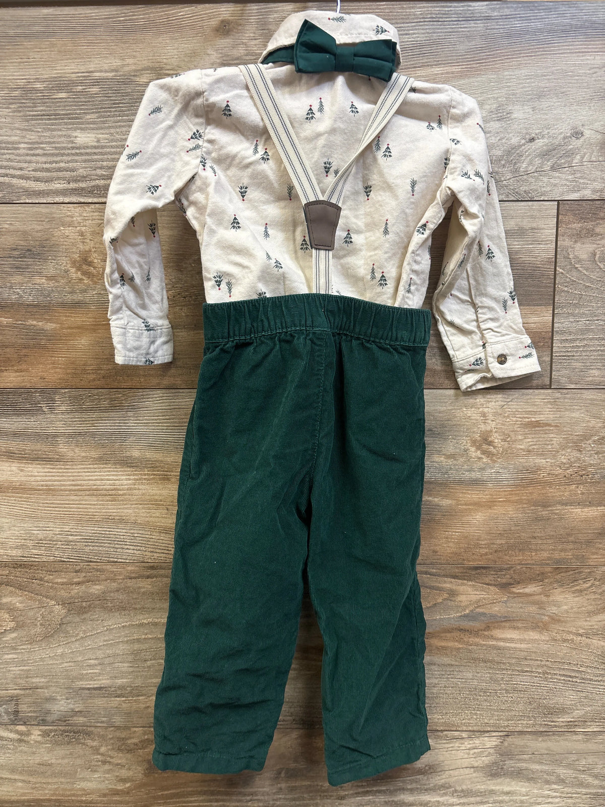Front view of Child Of Mine 4pc Christmas suspender set with tree-print shirt, bow tie, suspenders, and green pants