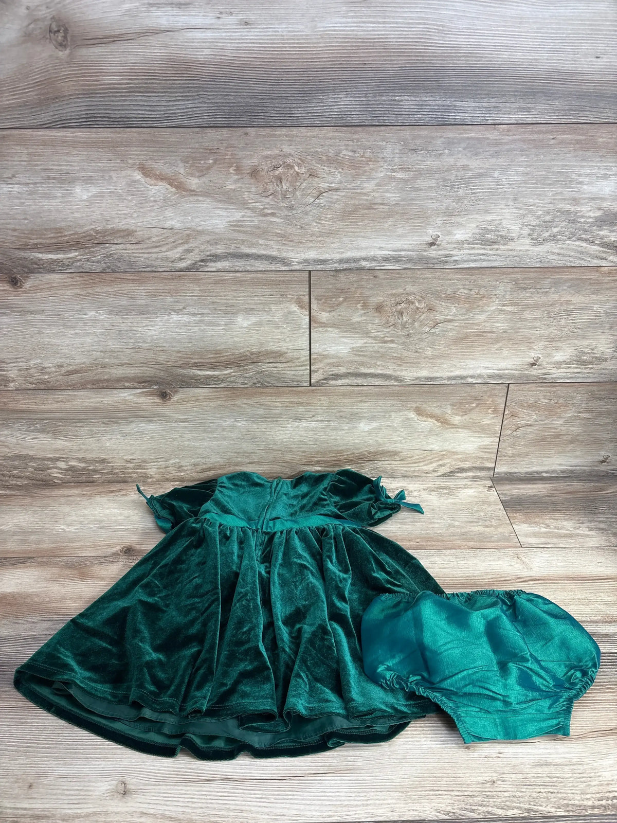 Green velvet toddler dress with matching bloomers on wood background