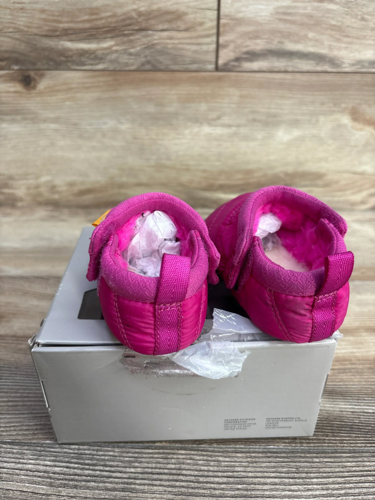 Rear view of UGG Tasman LTA baby boots in bright pink showing plush lining with heel pull tabs on white shoebox
