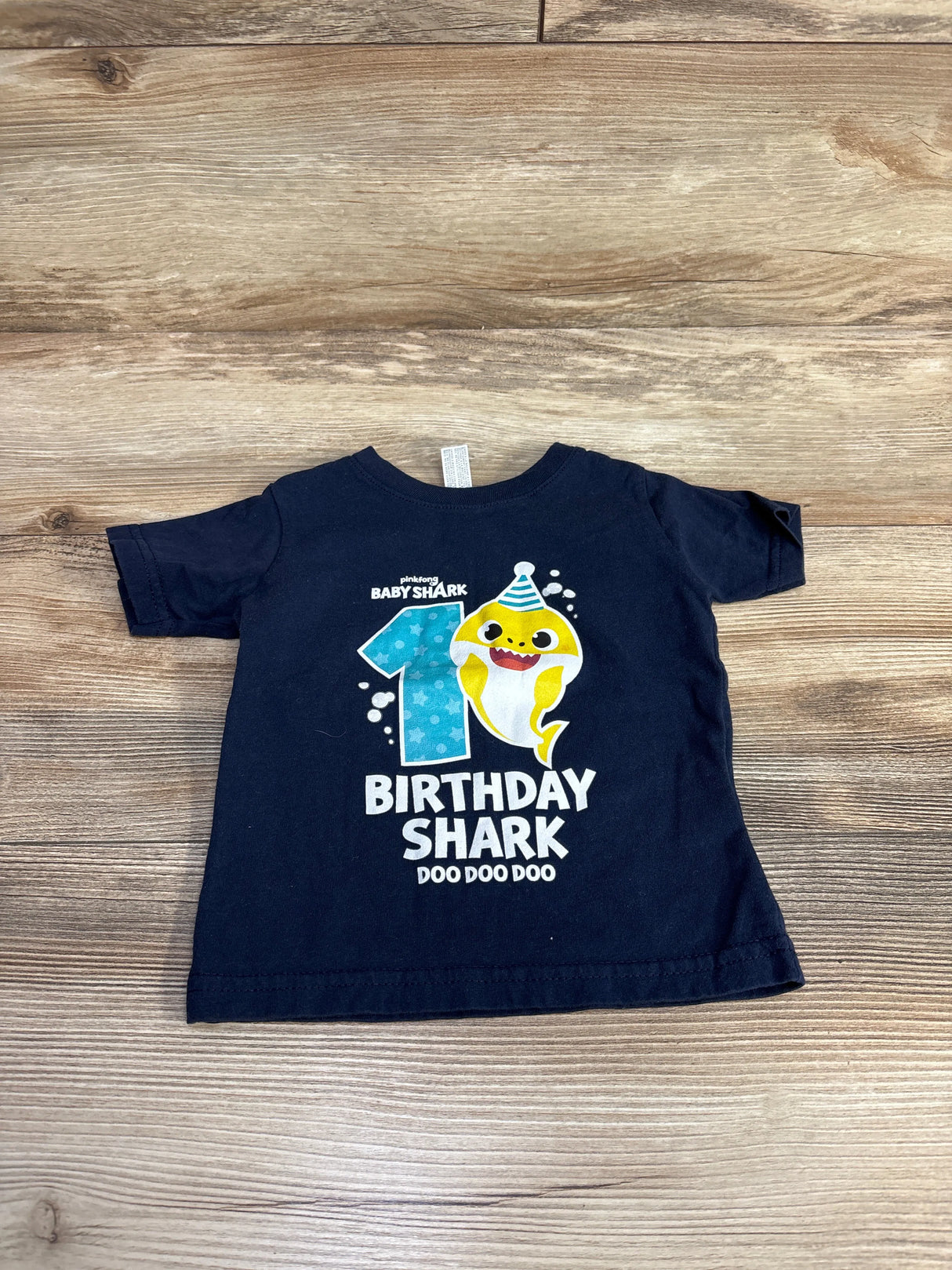Navy blue Baby Shark birthday T-shirt with cartoon shark and number 1 on wooden floor