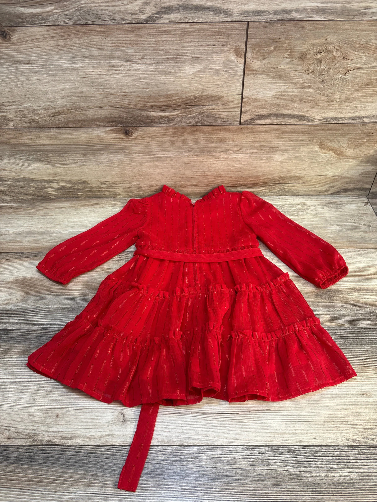Red long sleeve ruffle toddler dress with metallic stripes on wood background