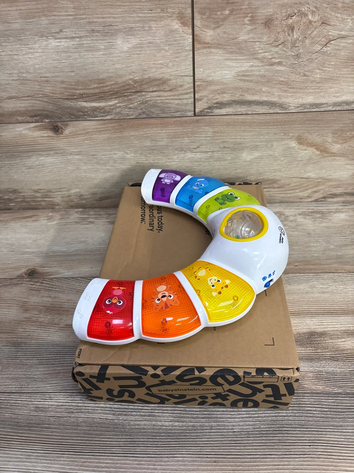 Angled view of Baby Einstein Glow & Discover Light Bar showcasing colorful animal panels and central light on a cardboard box