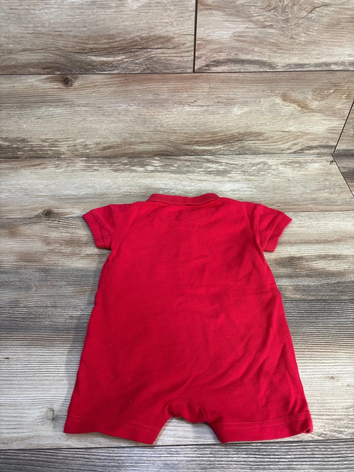 Back view of Baby Gap Henley polo romper showcasing short sleeves and collar on wood floor background