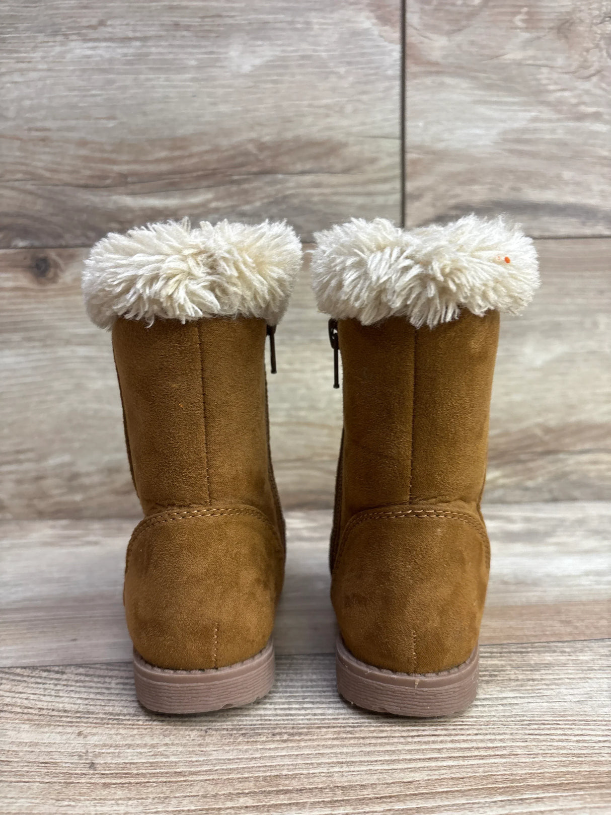 Brown kids' winter boots with cream faux fur cuffs, soft suede texture, and rubber soles on wood surface