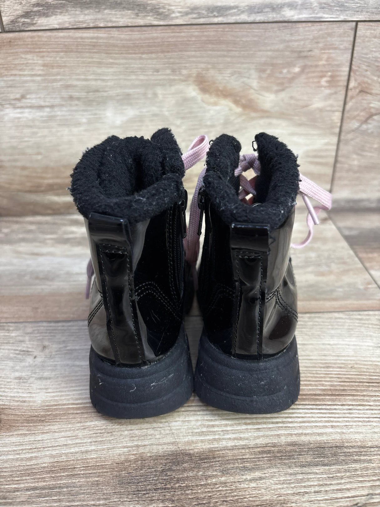 Pair of black children's winter boots with pink laces and soft lining on wood floor
