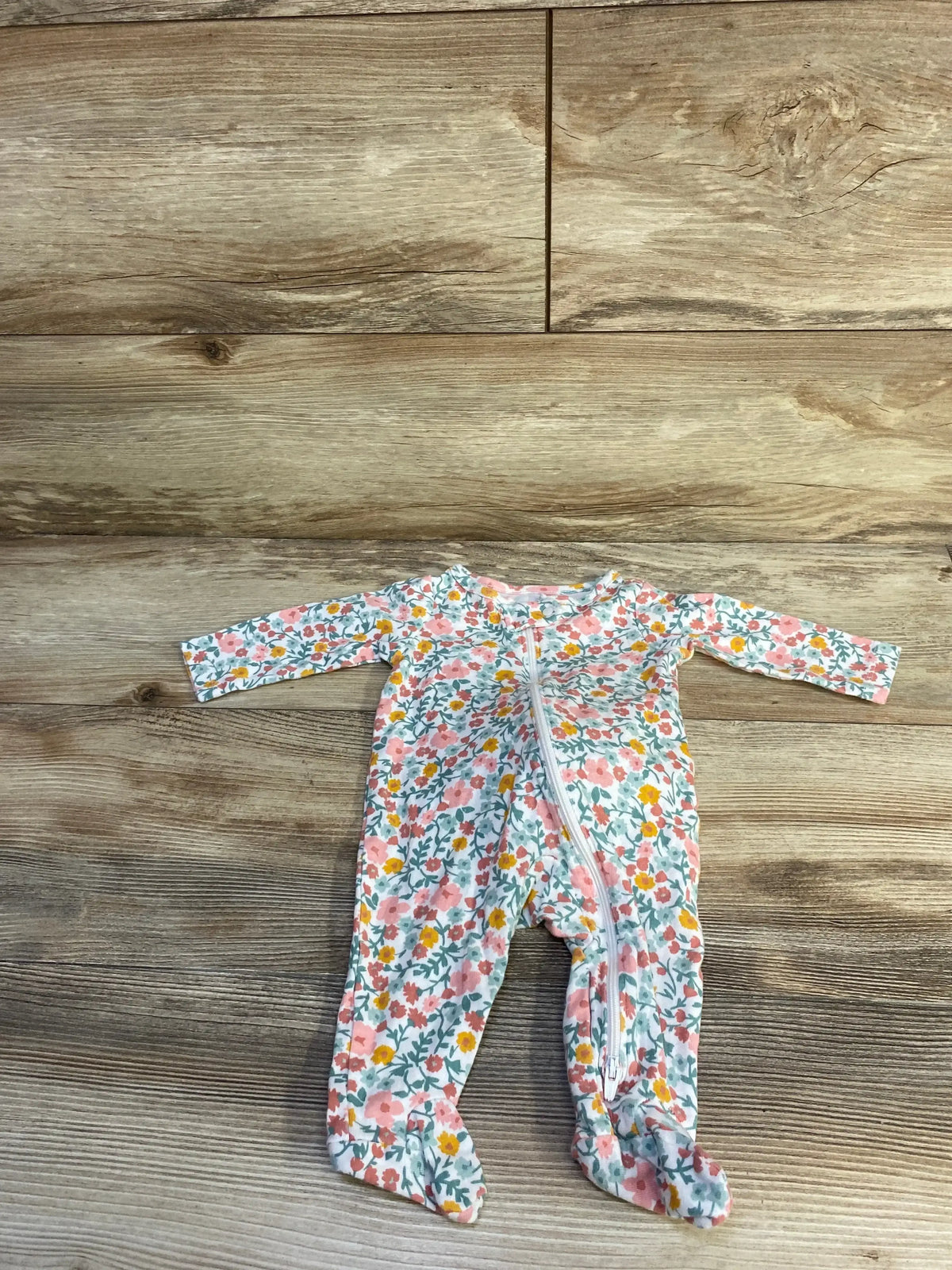 Front flat lay of white floral footed baby sleeper size 3 months showing diagonal zip closure and long sleeves on wood floor