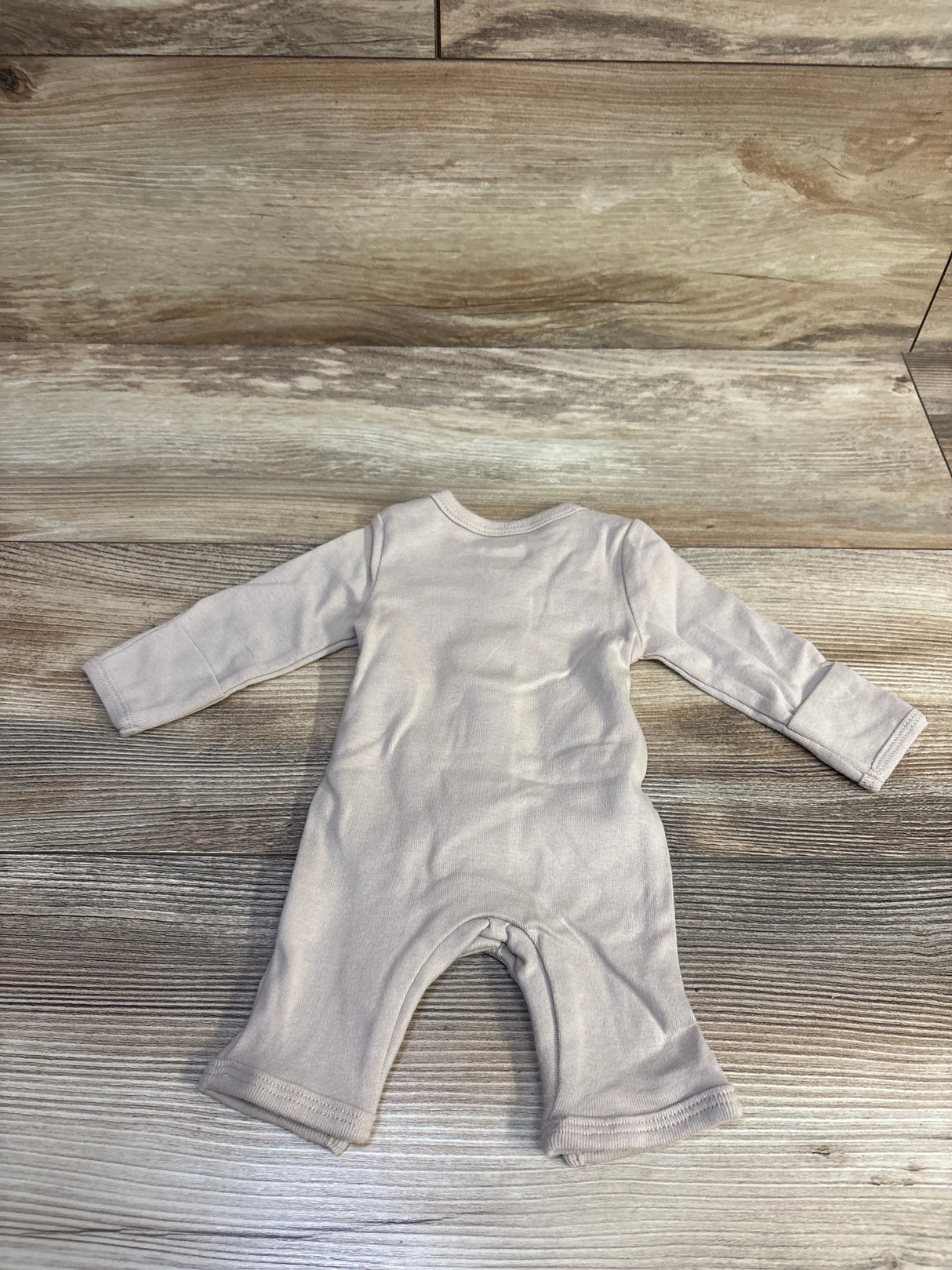 Back view of Cloud Island hook-and-loop coverall in tan, preemie size, long sleeves with fold-over cuffs on wood background