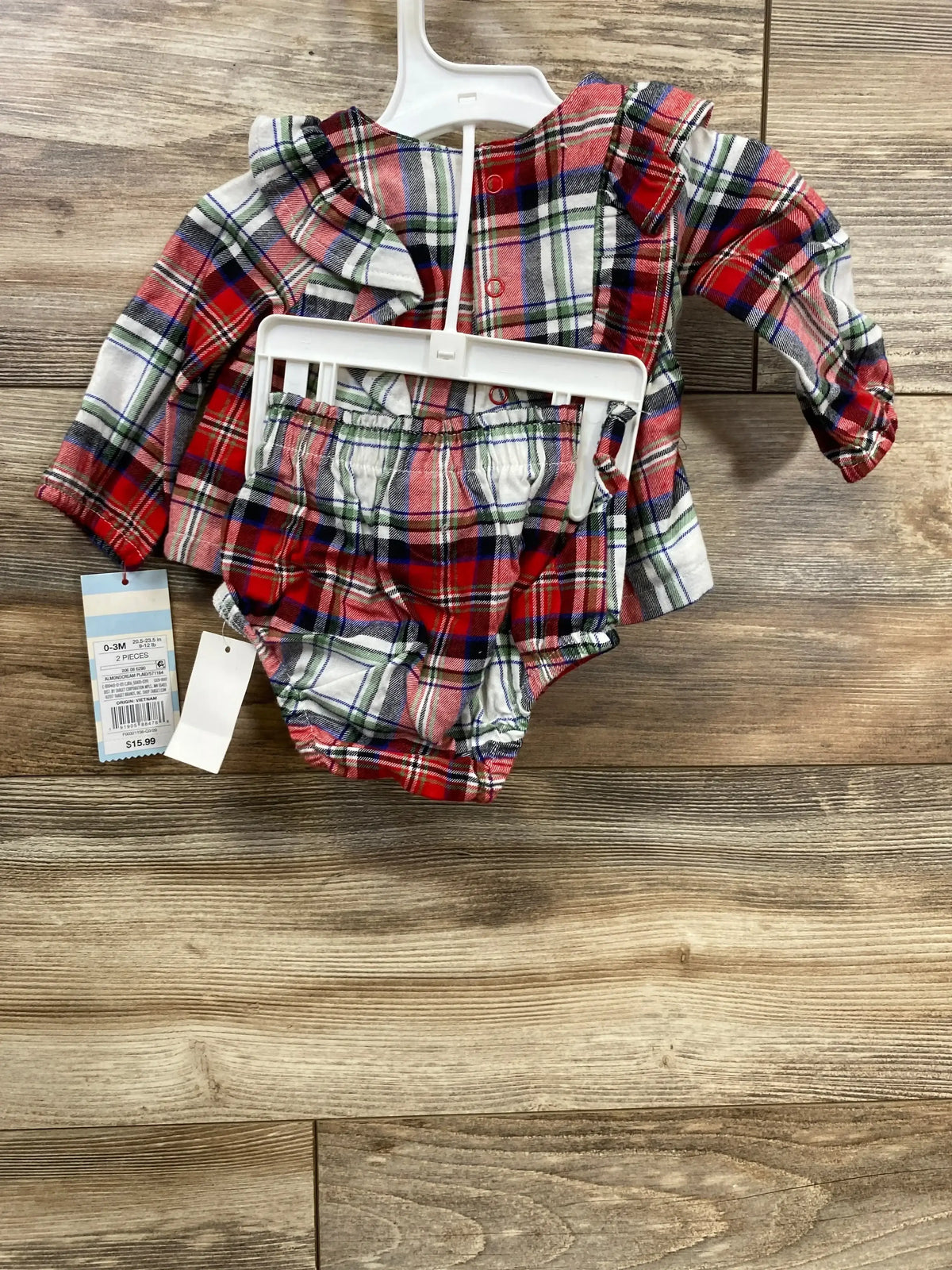 Flat-lay of Cat & Jack 2-piece red plaid top and bottoms, size 0-3M, with ruffle collar and long sleeves on wood floor