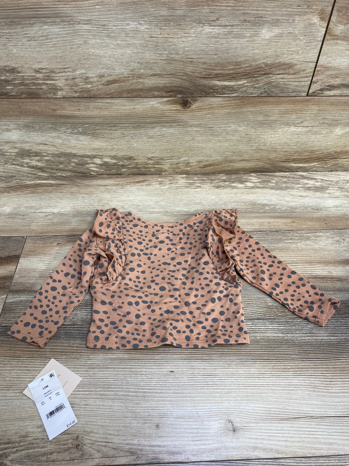 Toddler long sleeve pink polka dot shirt with ruffle shoulders on wood background