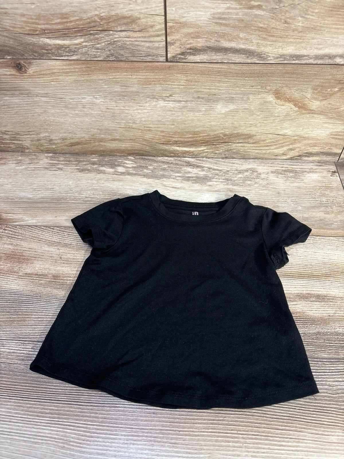Flat lay of Ideology toddler black active shirt (size 2T) showing short sleeves, crew neck, and slight A-line hem on wood background