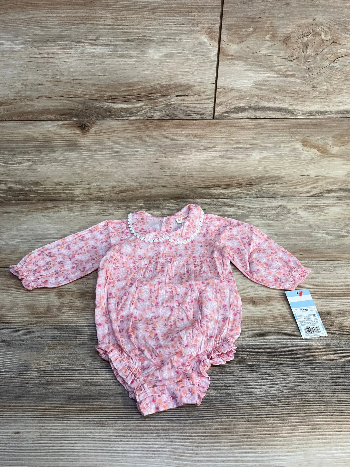Top view of pink floral baby romper (3–6M) with scalloped lace collar, long sleeves, ruffled elastic legs and snap crotch