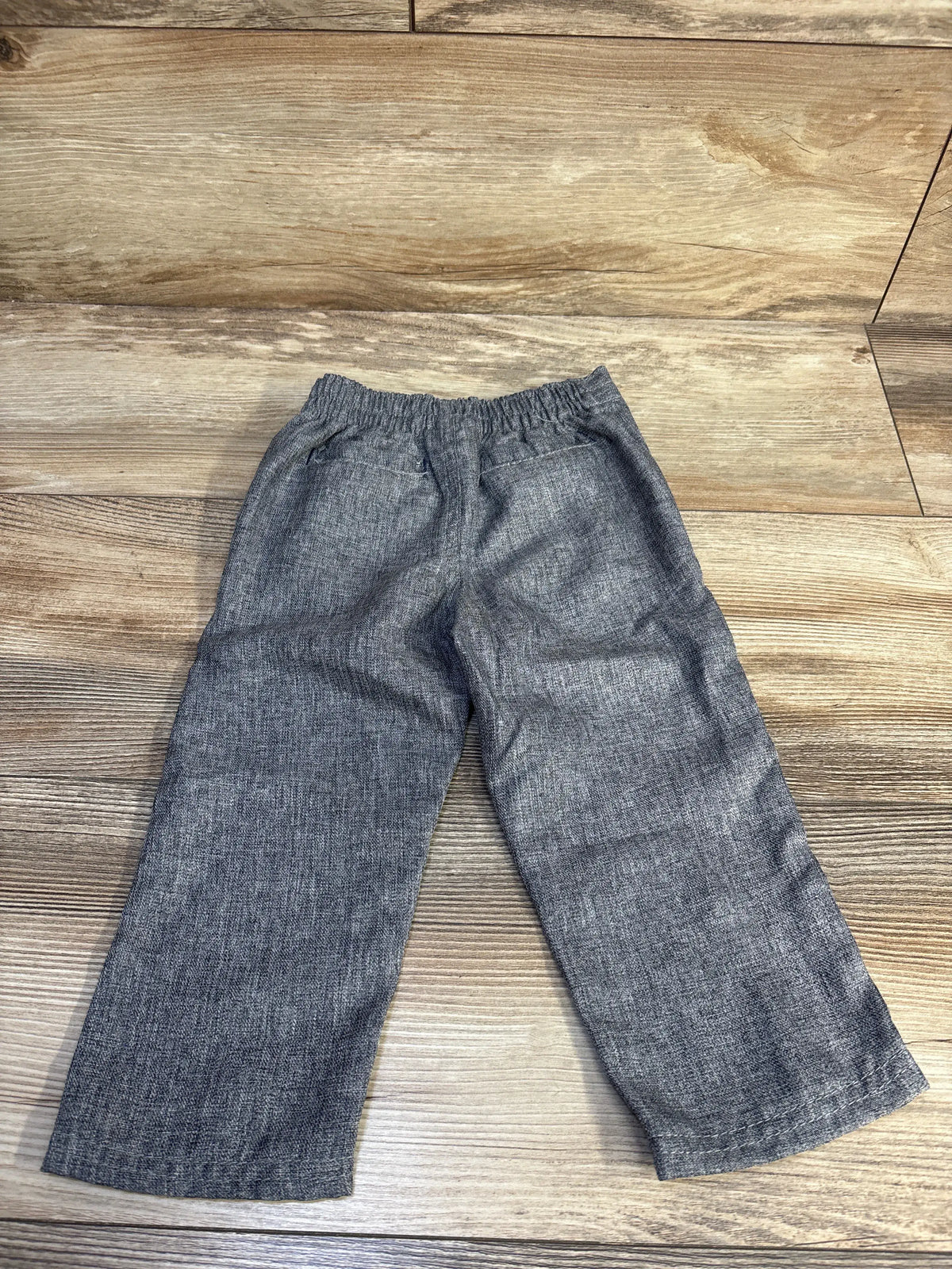 Front view of Tahari grey wide leg pants, size 18 months, showcasing elastic waistband and front pockets on wood planks