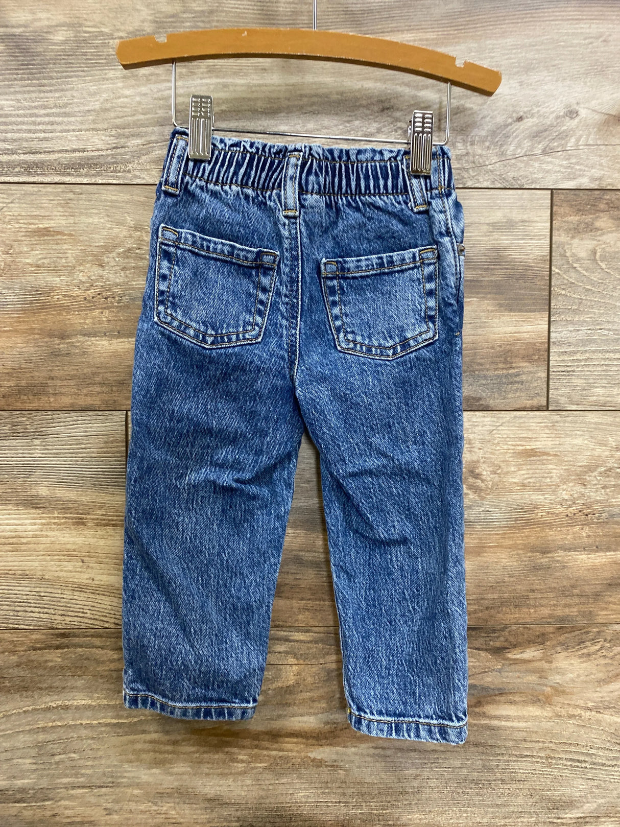 Kids blue denim jeans with elastic waistband and back pockets, displayed on hanger