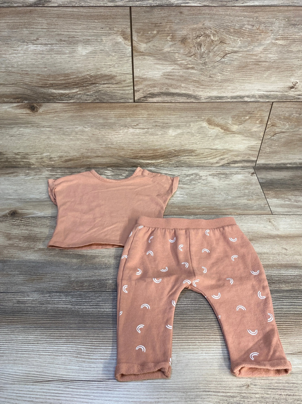 Top view of Grayson Mini 2pc set in tan, size 0 to 3 months, with short-sleeve shirt and rainbow pants on wood