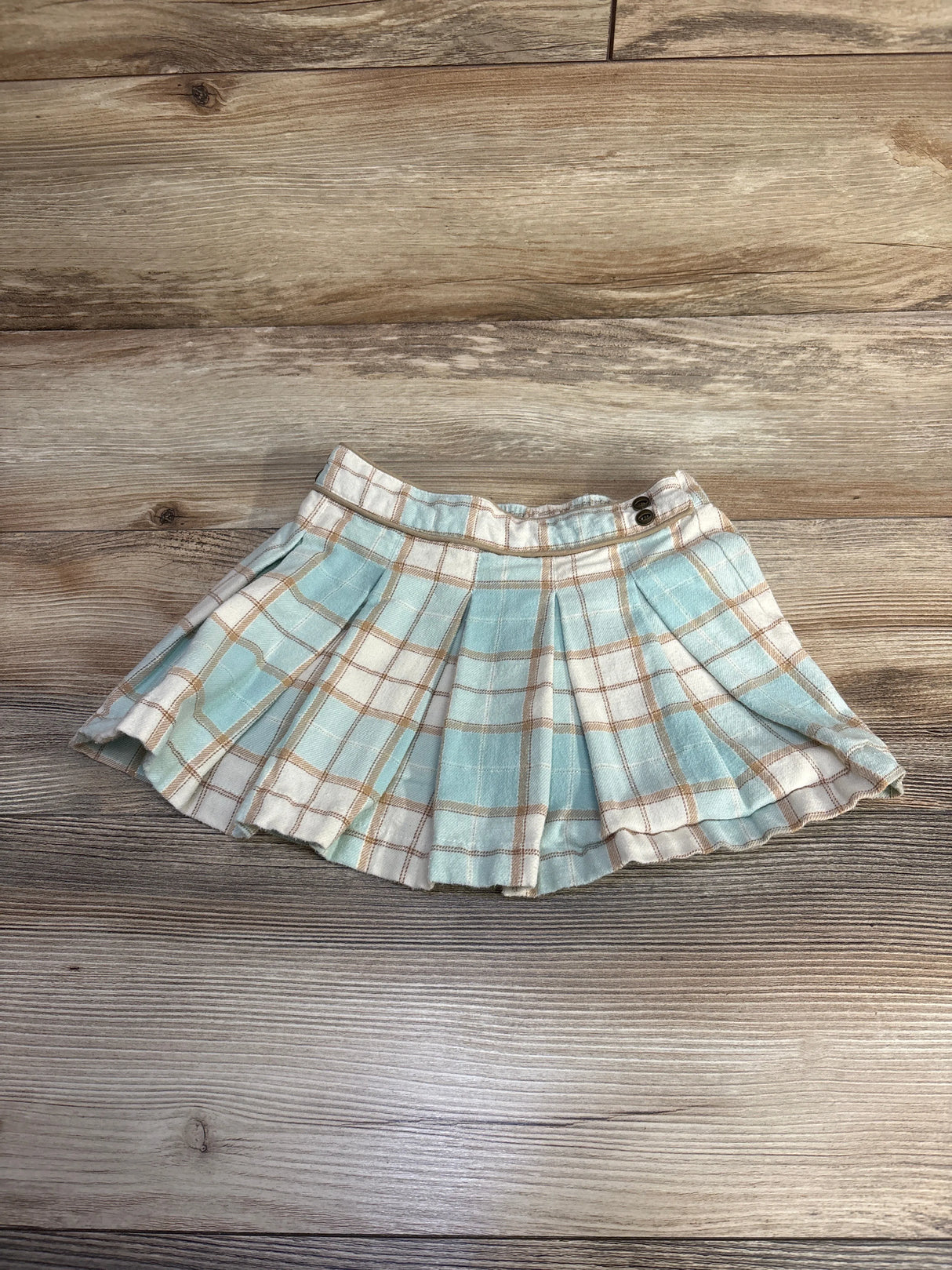 Pleated mini skirt with blue and white plaid pattern on wooden surface