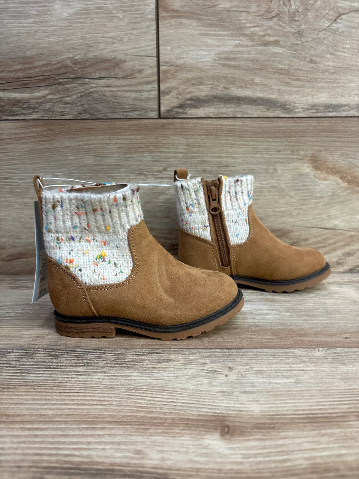 Tan suede toddler boots with knitted cuffs and side zippers on wood background