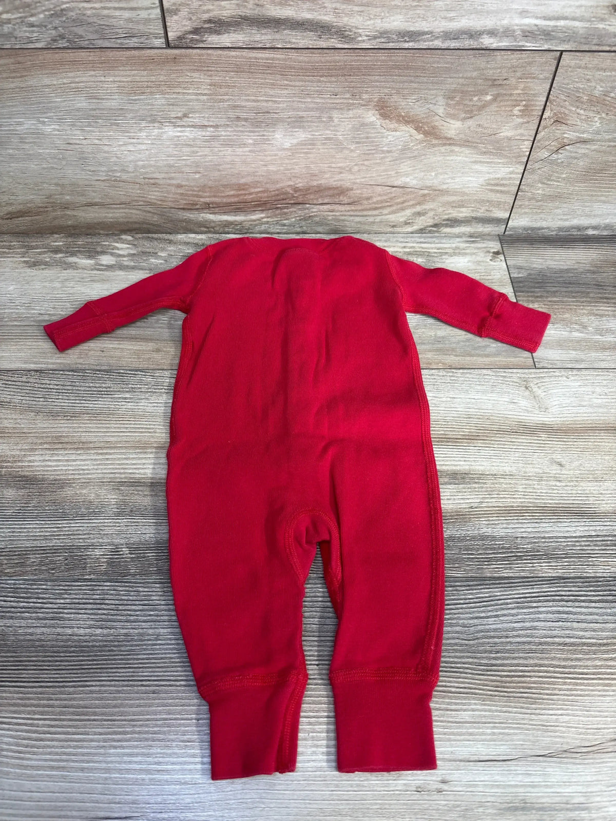 Red baby onesie laid flat on wood floor, soft ribbed fabric, long sleeves, ideal for infant clothing resale