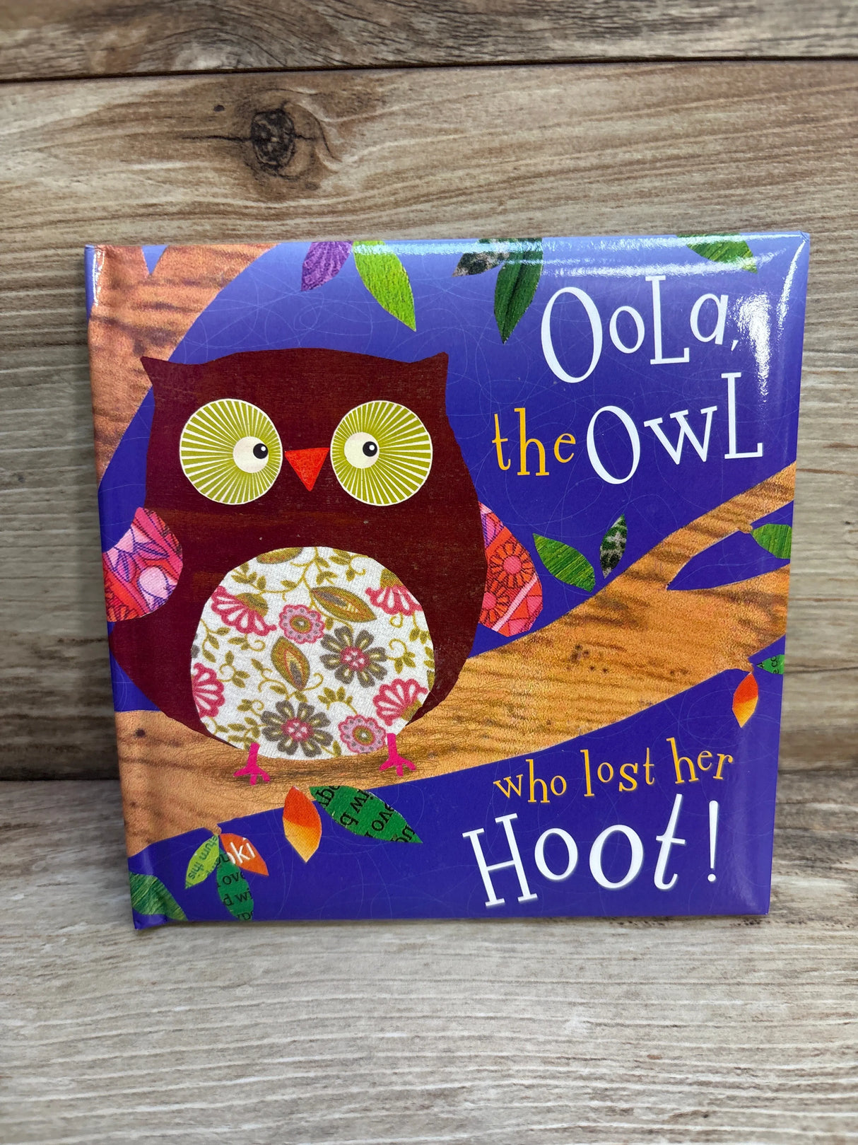 Children's book cover with colorful owl illustration, Oola the Owl who lost her hoot, wood background