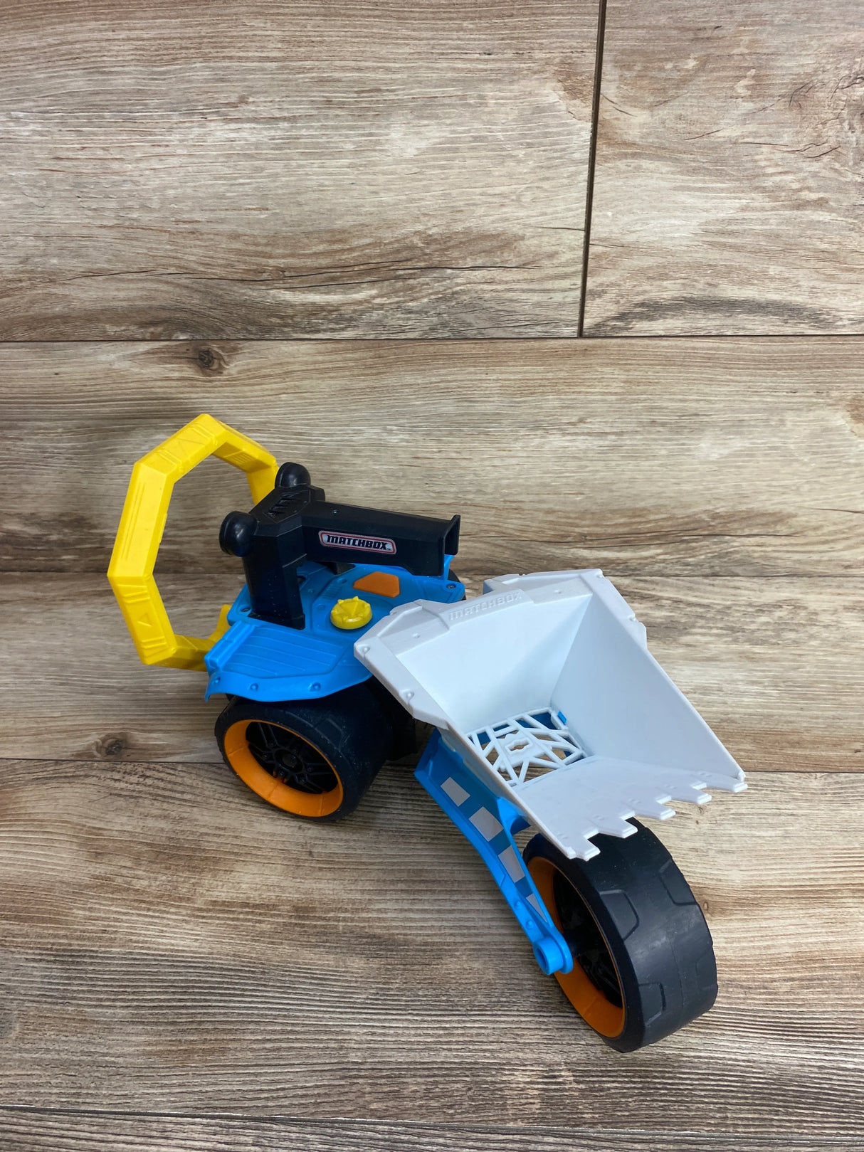 Matchbox blue and white toy construction loader with yellow handle on wood floor