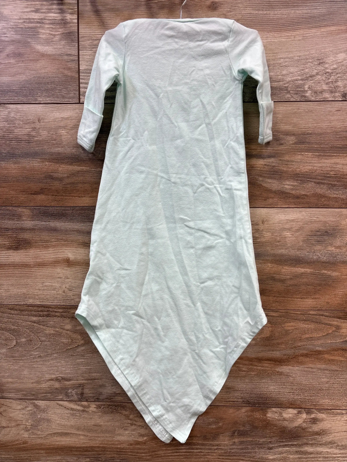Flat-lay of Baby Noah knotted gown in light blue showing long sleeves and knotted bottom on wood background