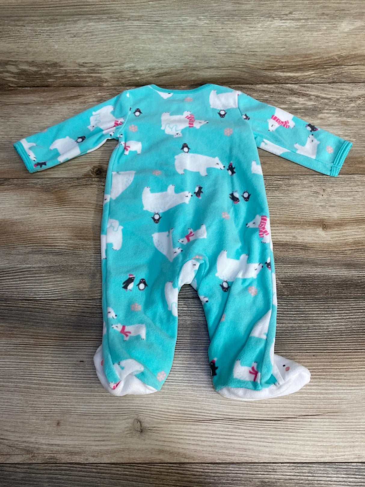 Back view of Carter’s blue polar bear blanket sleeper showing footed legs and all-over polar bear and penguin print on wooden floor