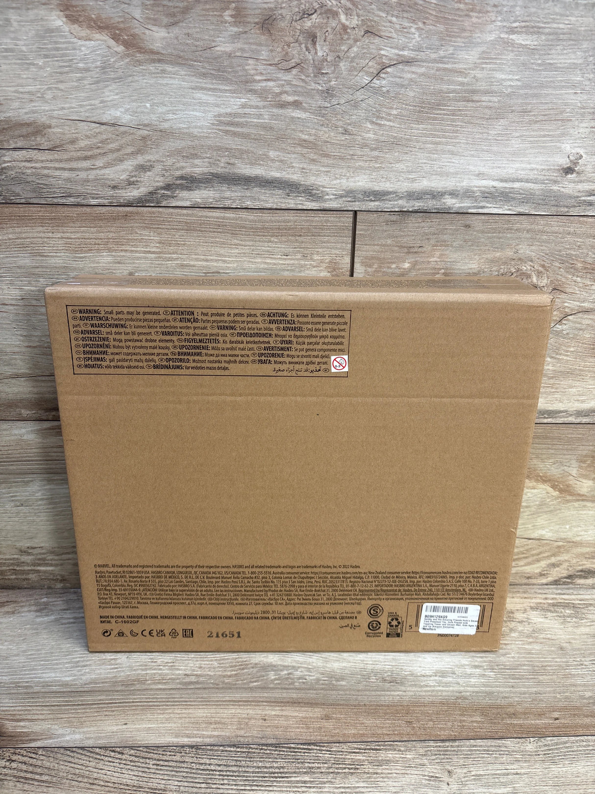 Brown cardboard toy box back with multilingual safety warnings and wood background