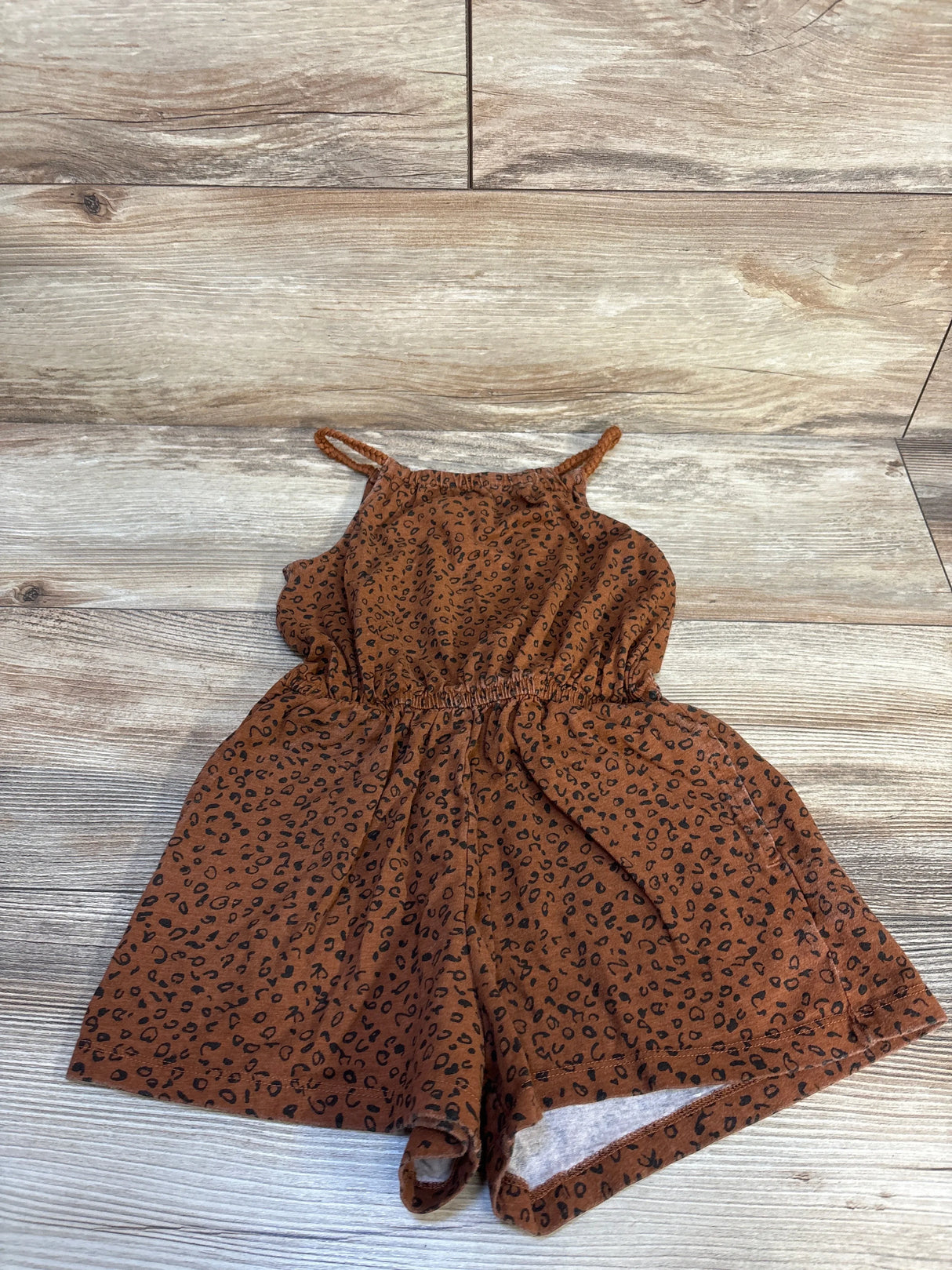 Brown leopard print toddler romper with spaghetti straps on wood background