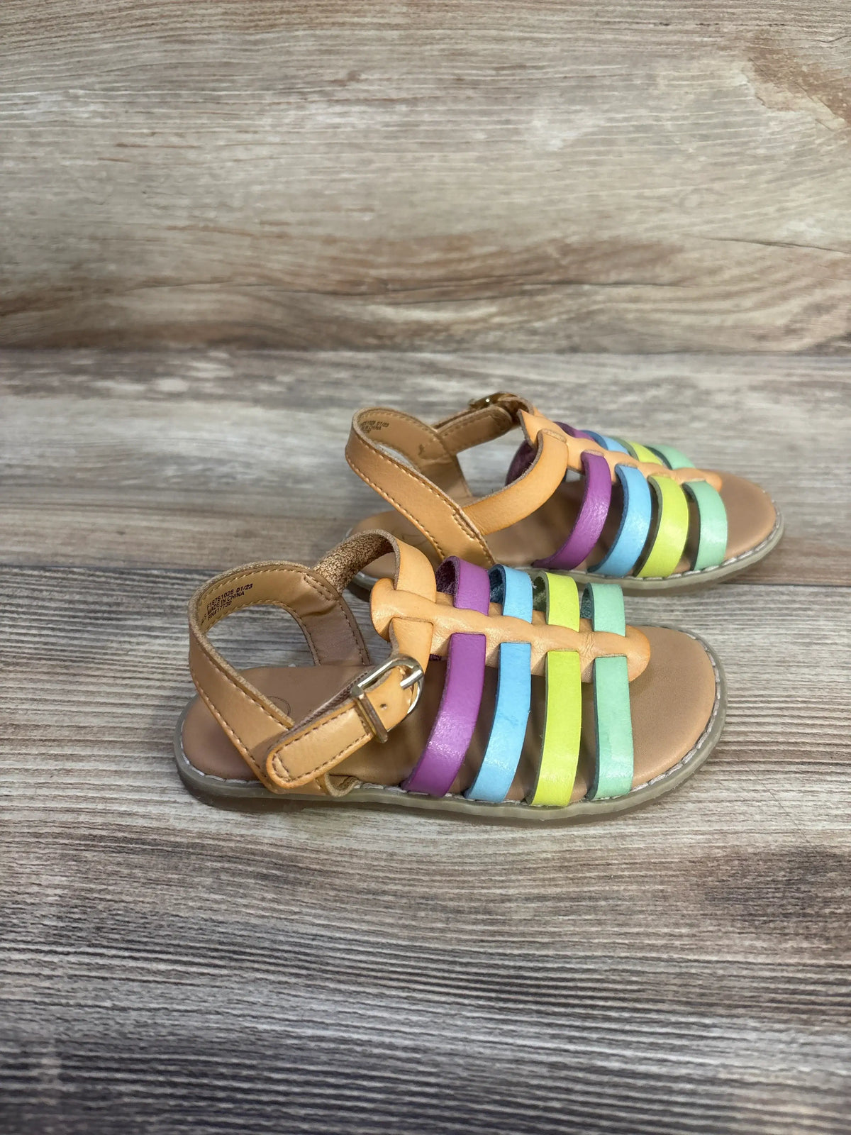 Three-quarter view of Cat & Jack Shanel fisherman sandals showcasing multicolored straps on a wood-grain surface