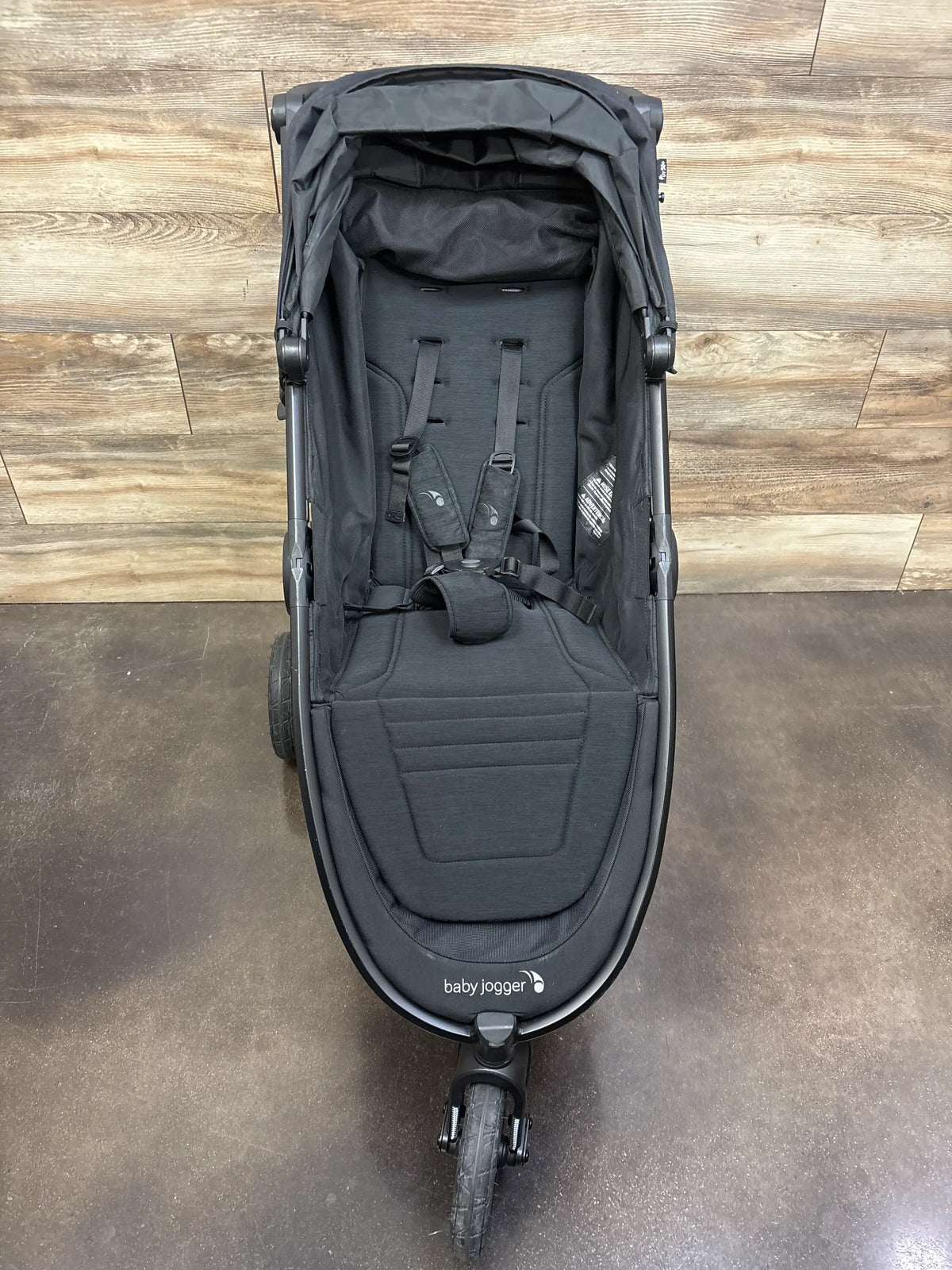 Front view of Baby Jogger City Mini GT2 All Terrain stroller in Opulent Black with padded seat and harness on wood flooring